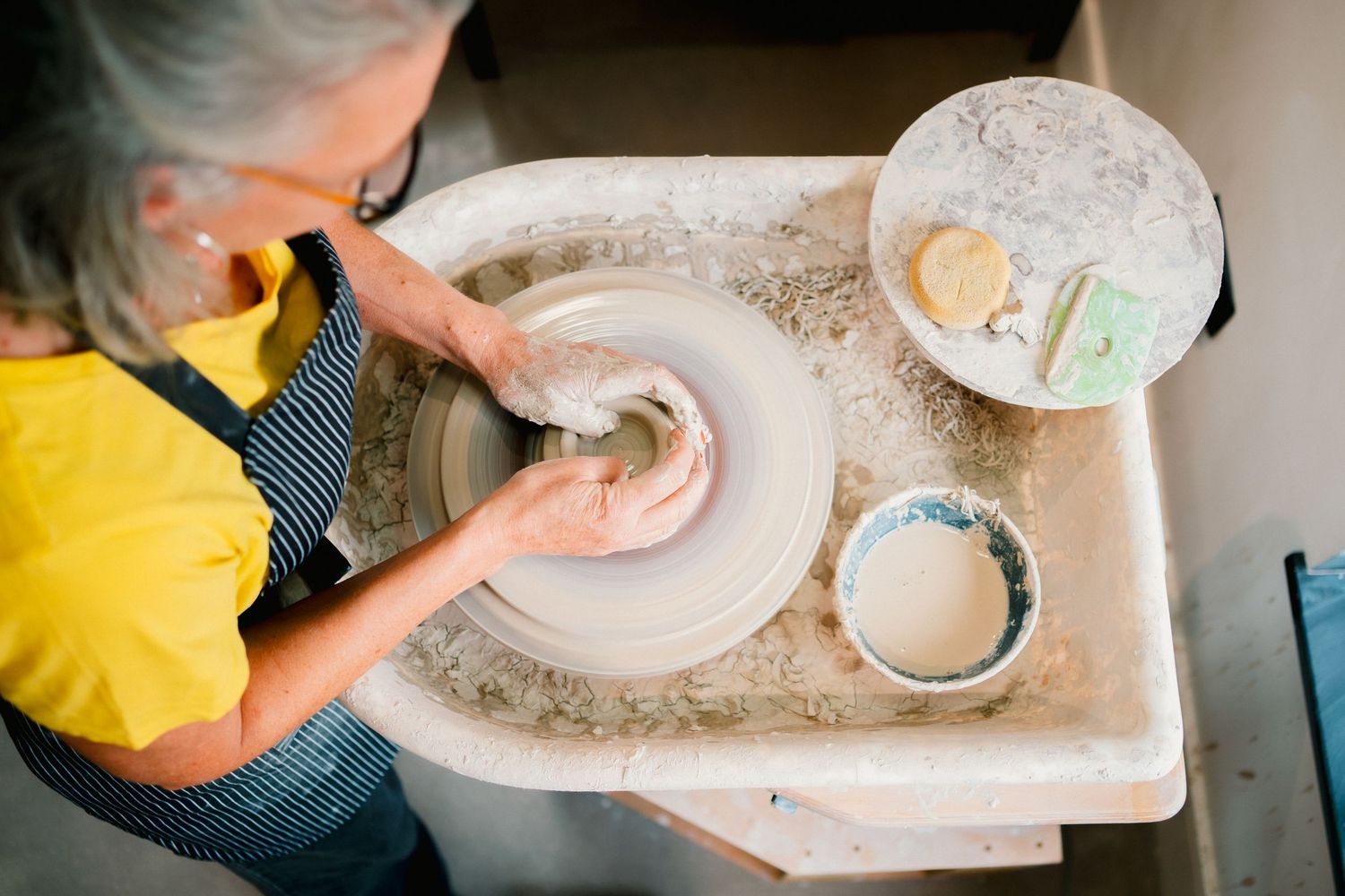 Close-up view of hands working with clay on pottery wheels during a ceramics workshop session.
