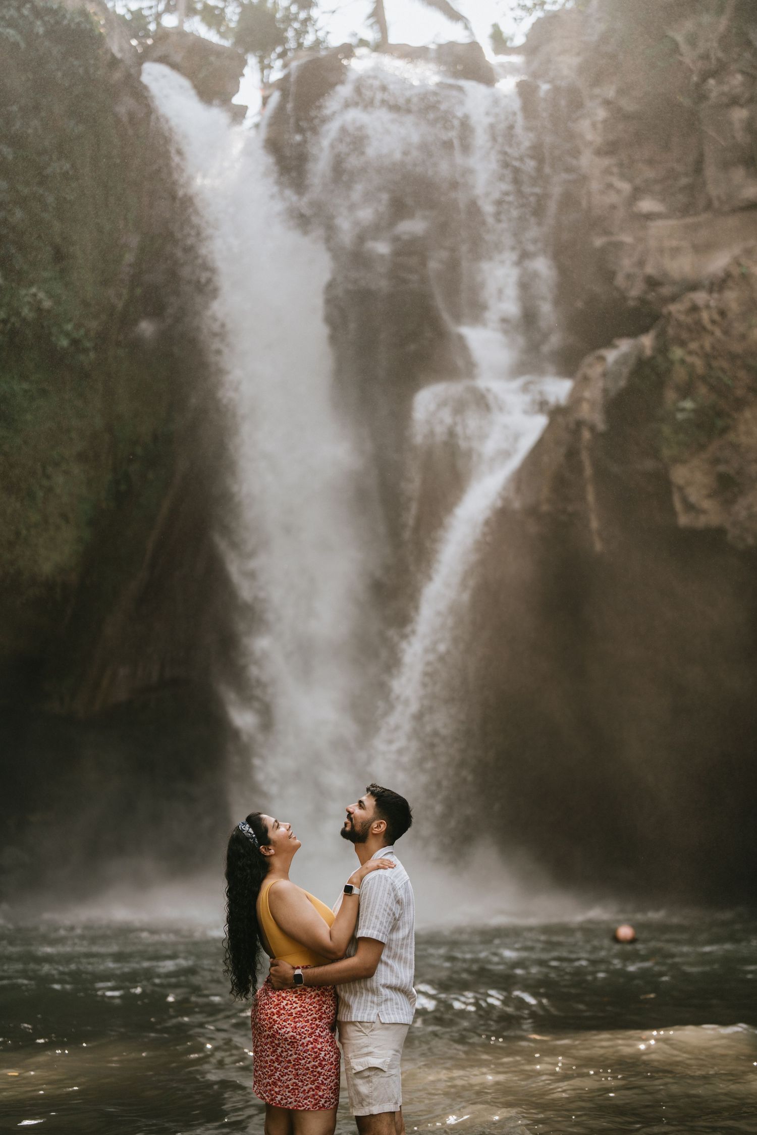 Couple sharing a romantic moment in front of a majestic waterfall.