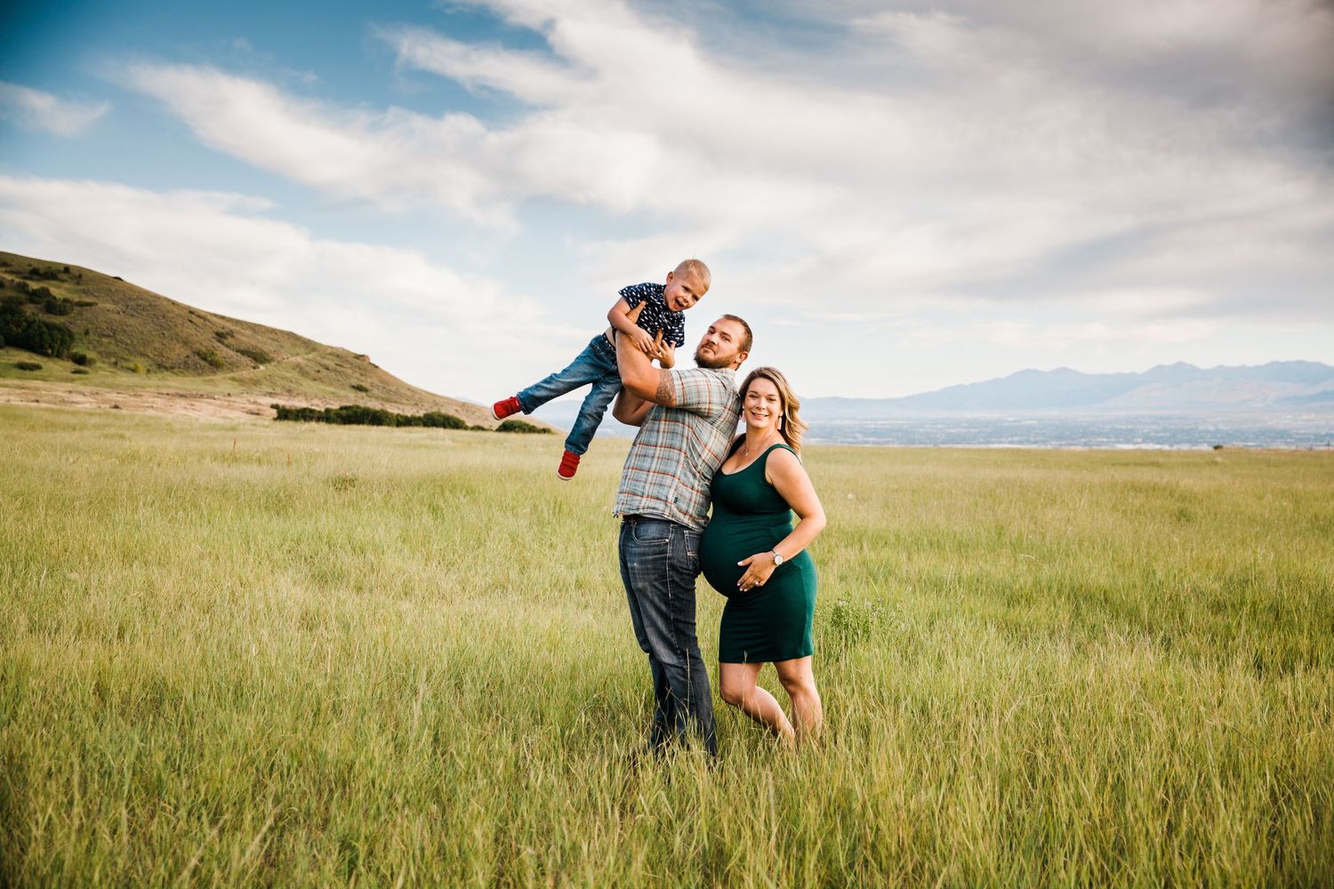 A couple dances playfully together in an open grassy field under cloudy skies.