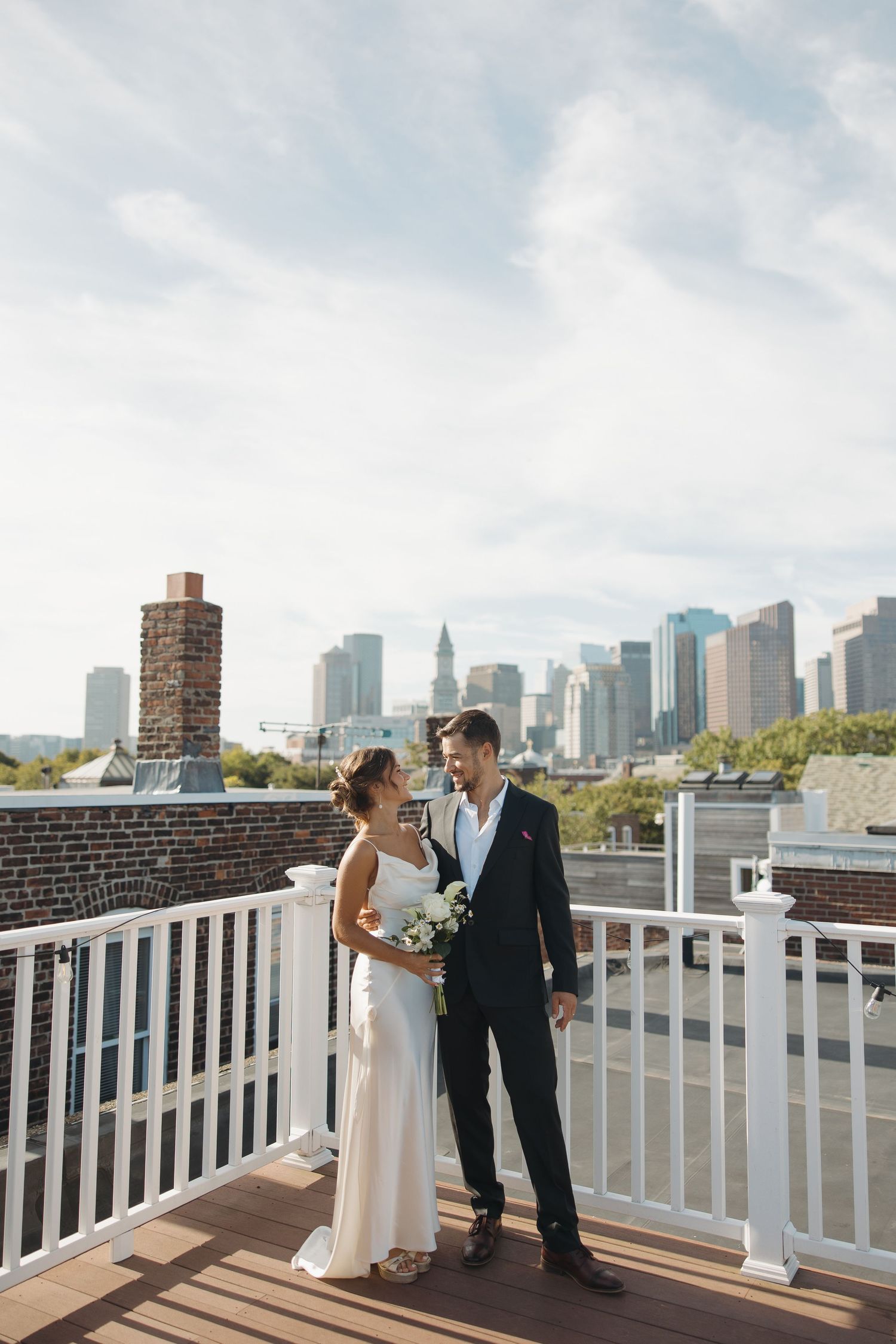 Rooftop wedding scene with Manhattan skyline backdrop on sunny day.