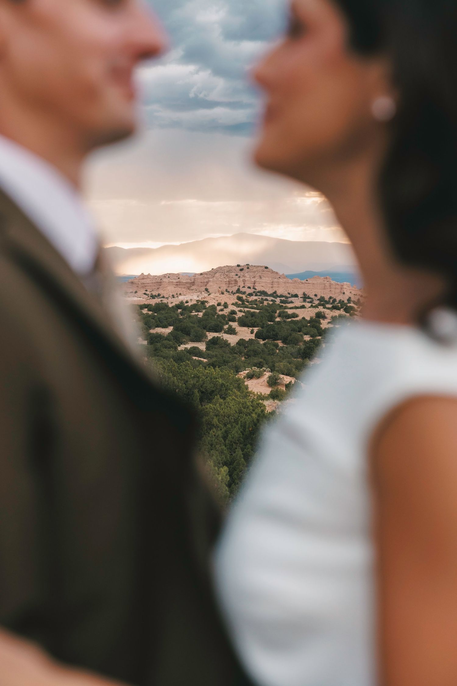 Creative wedding portrait framing scenic desert landscape between bride and groom.