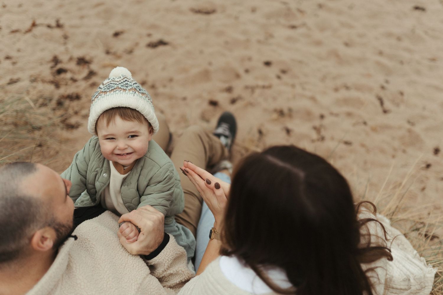 A collection of candid black and white beach photos showing joyful moments between people playing in the sand.