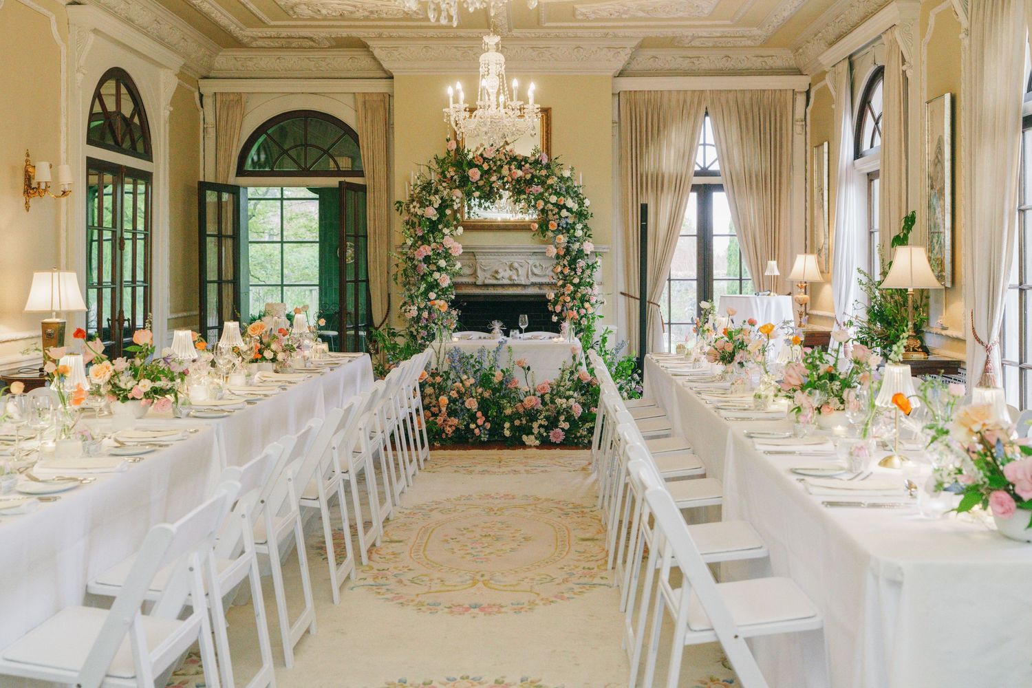 Black and white wedding photo of bride and groom sharing a romantic moment at elegant altar with floral arrangements.
