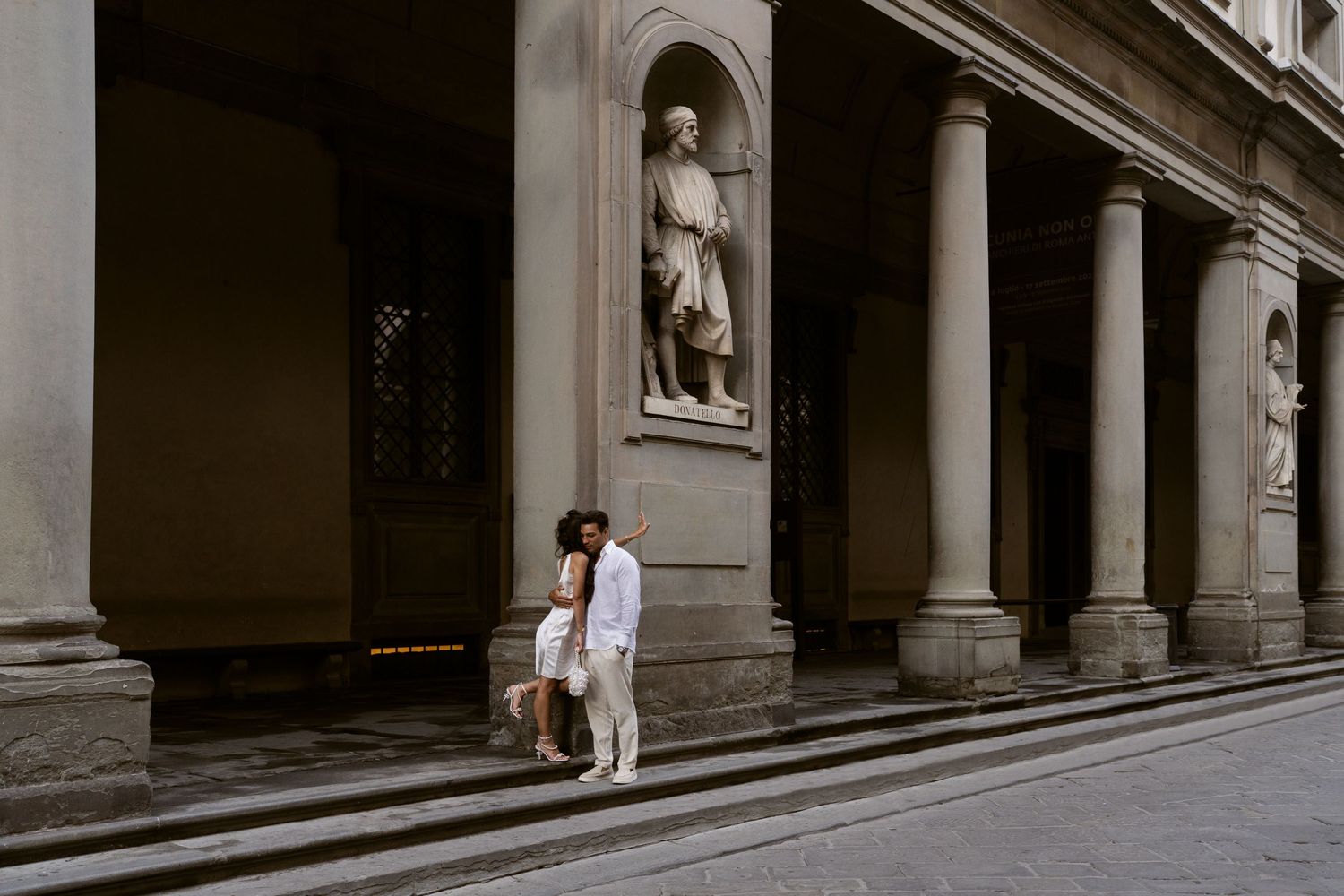 Couple holding hands by the Ponte Vecchio bridge over the Arno River in Florence, Italy at golden hour.