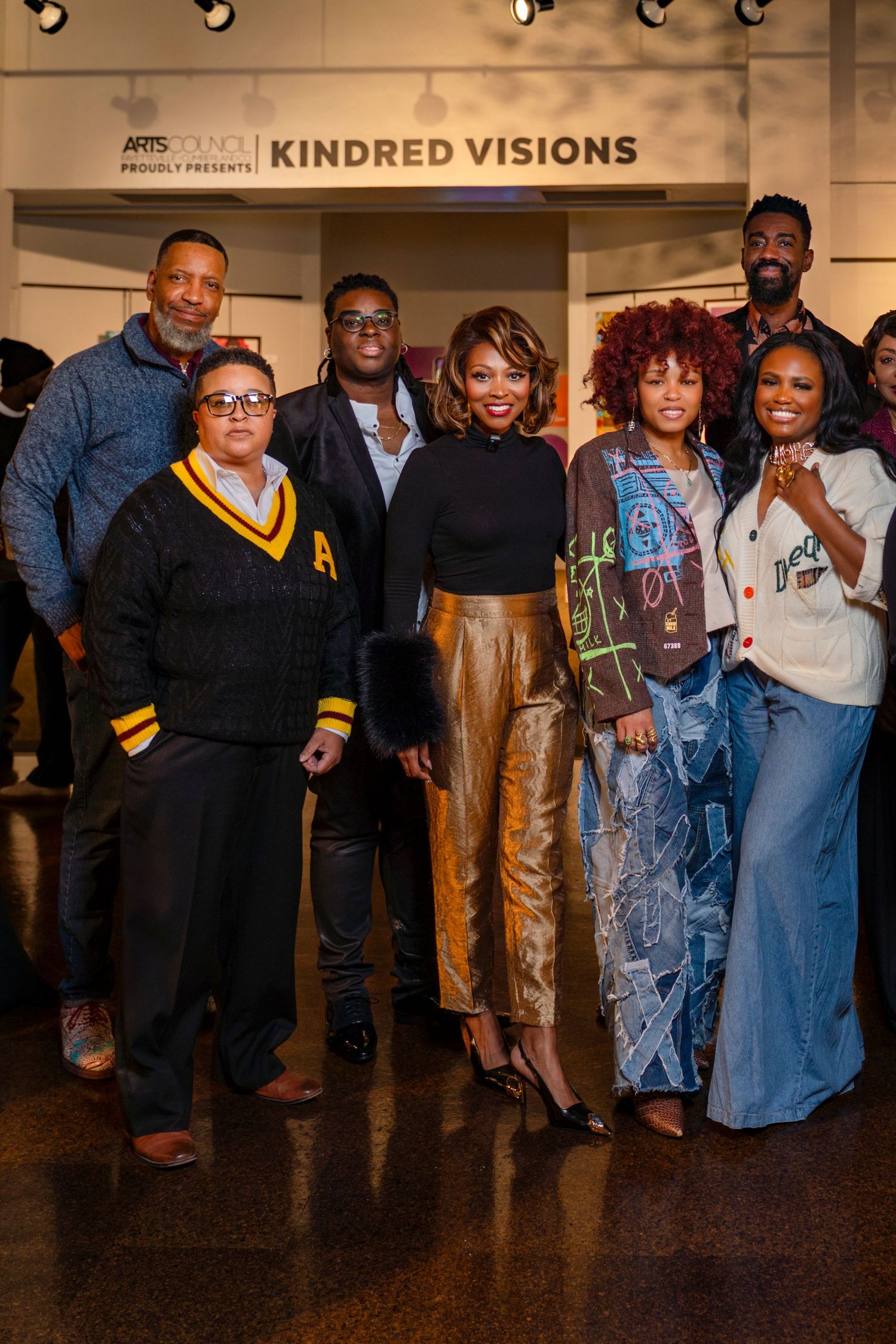 A group of people gathered at the Kindred Visions art exhibition standing together in casual and formal attire.