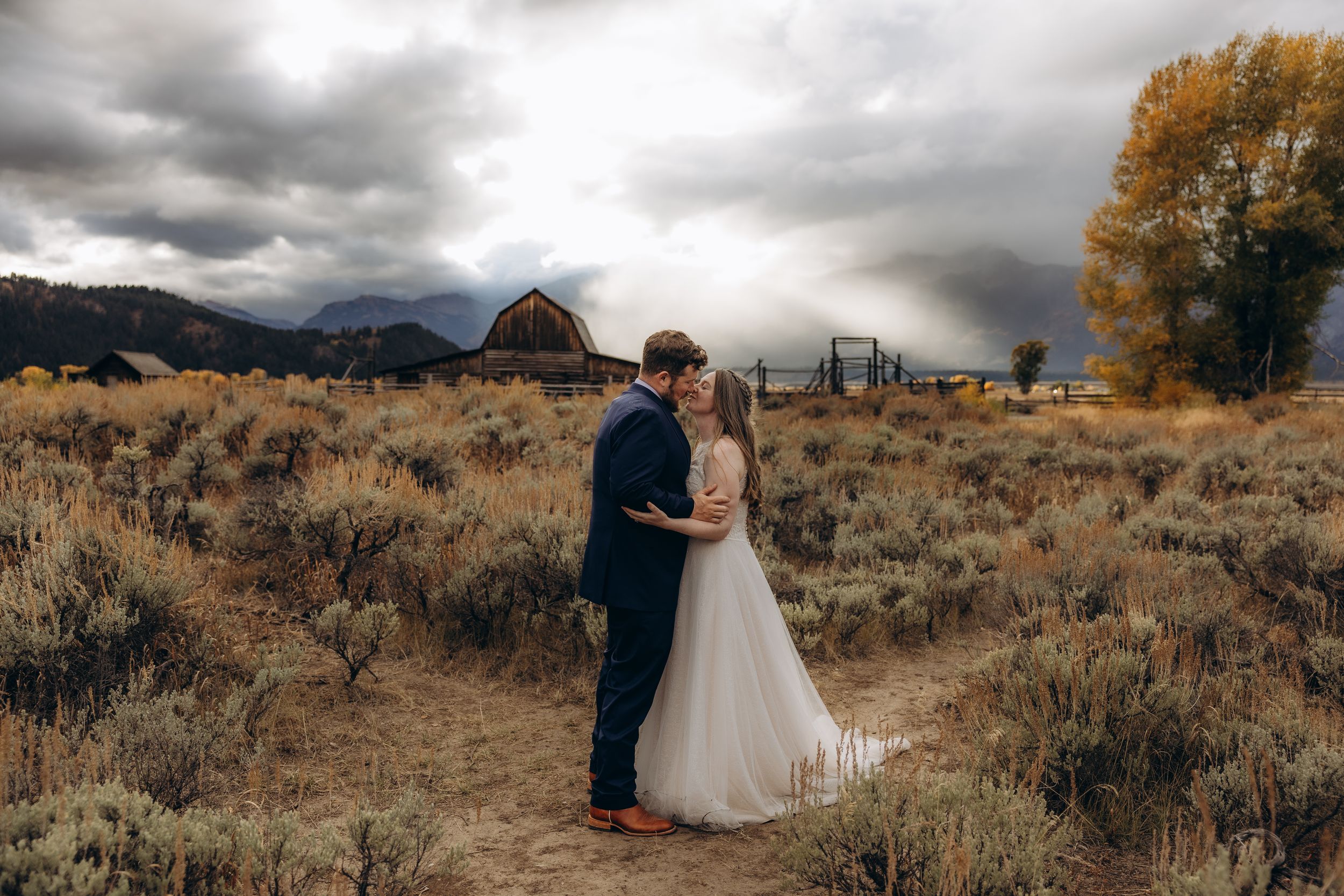 A romantic wedding photo series showing a couple embracing against dramatic mountain and desert landscapes at sunset.