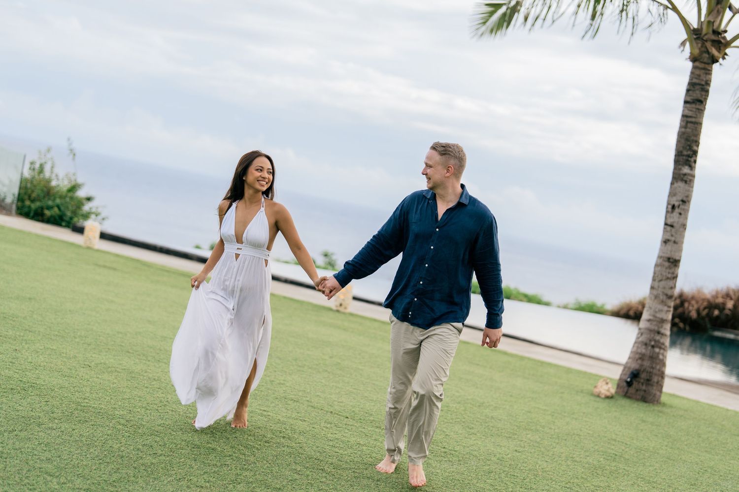 Couple walking along a green garden pathway surrounded by tropical plants.