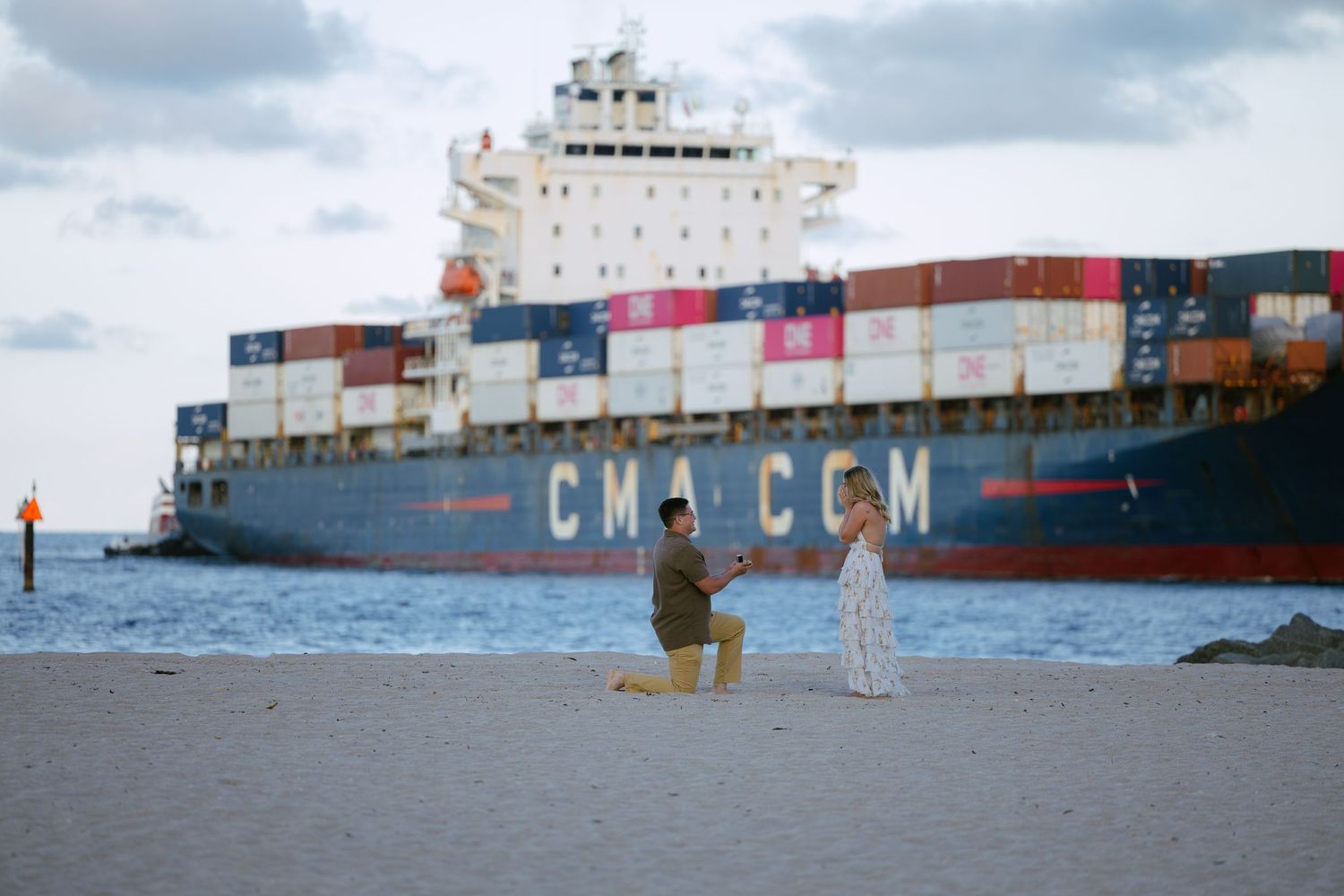 man proposing to girlfriend on the beach in Fort Lauderdale with a cargo ship behind them