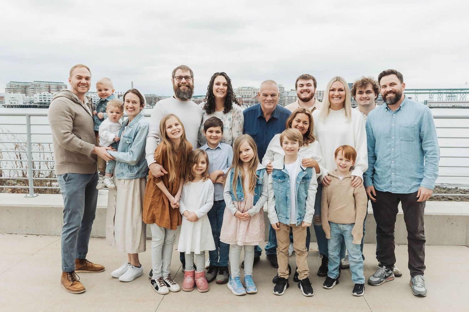 Large family group portrait on waterfront boardwalk with marina in background.