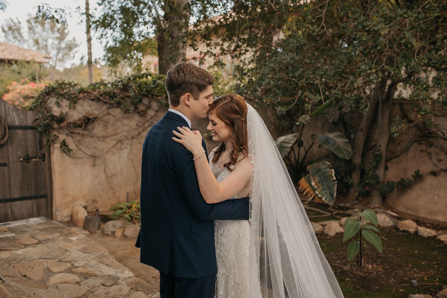 Elegant outdoor wedding photoshoot with stone walls and natural greenery in the background at Rancho Buena Vista Adobe.