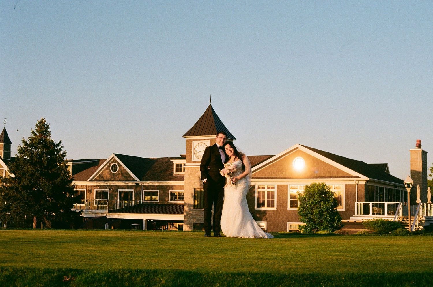 Golden hour wedding portrait with couple standing before a grand country club building.