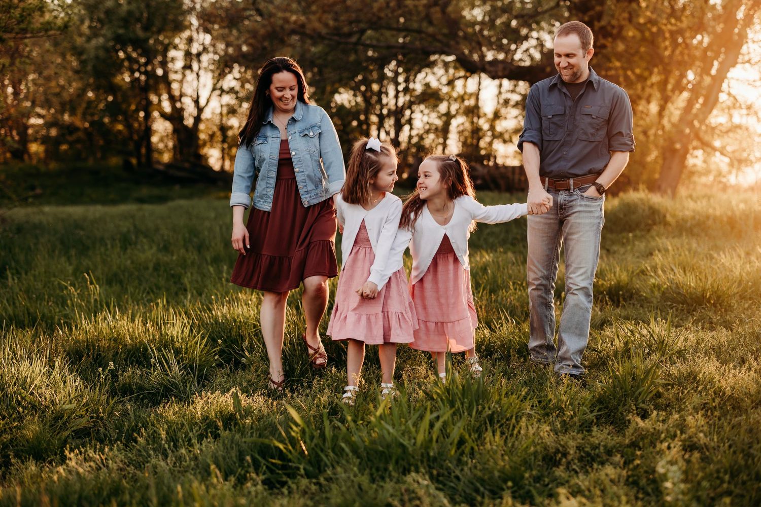 Family enjoys golden hour photography session in a grassy field at sunset.