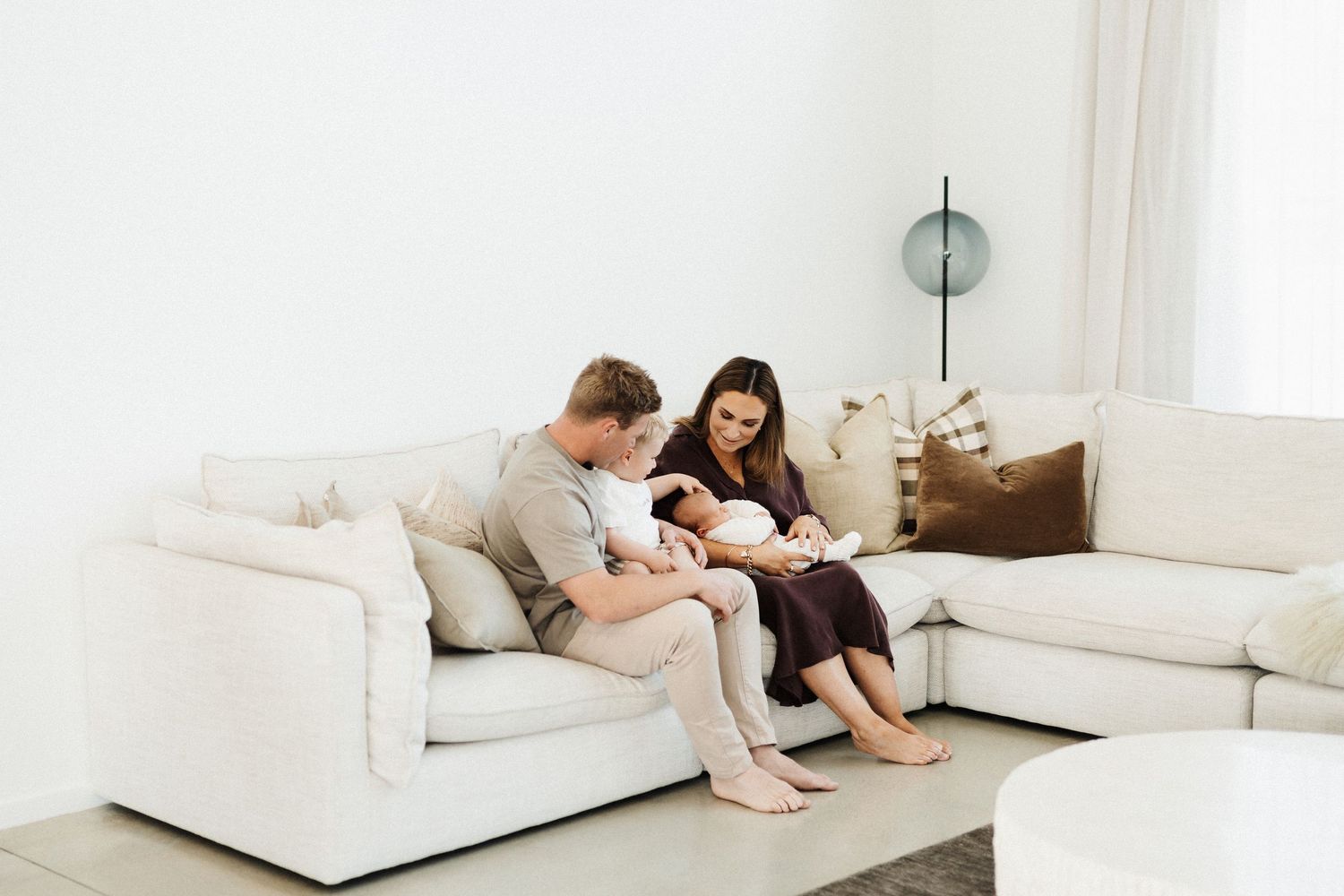 A couple lounges comfortably together on a plush white sofa in a bright modern living room.
