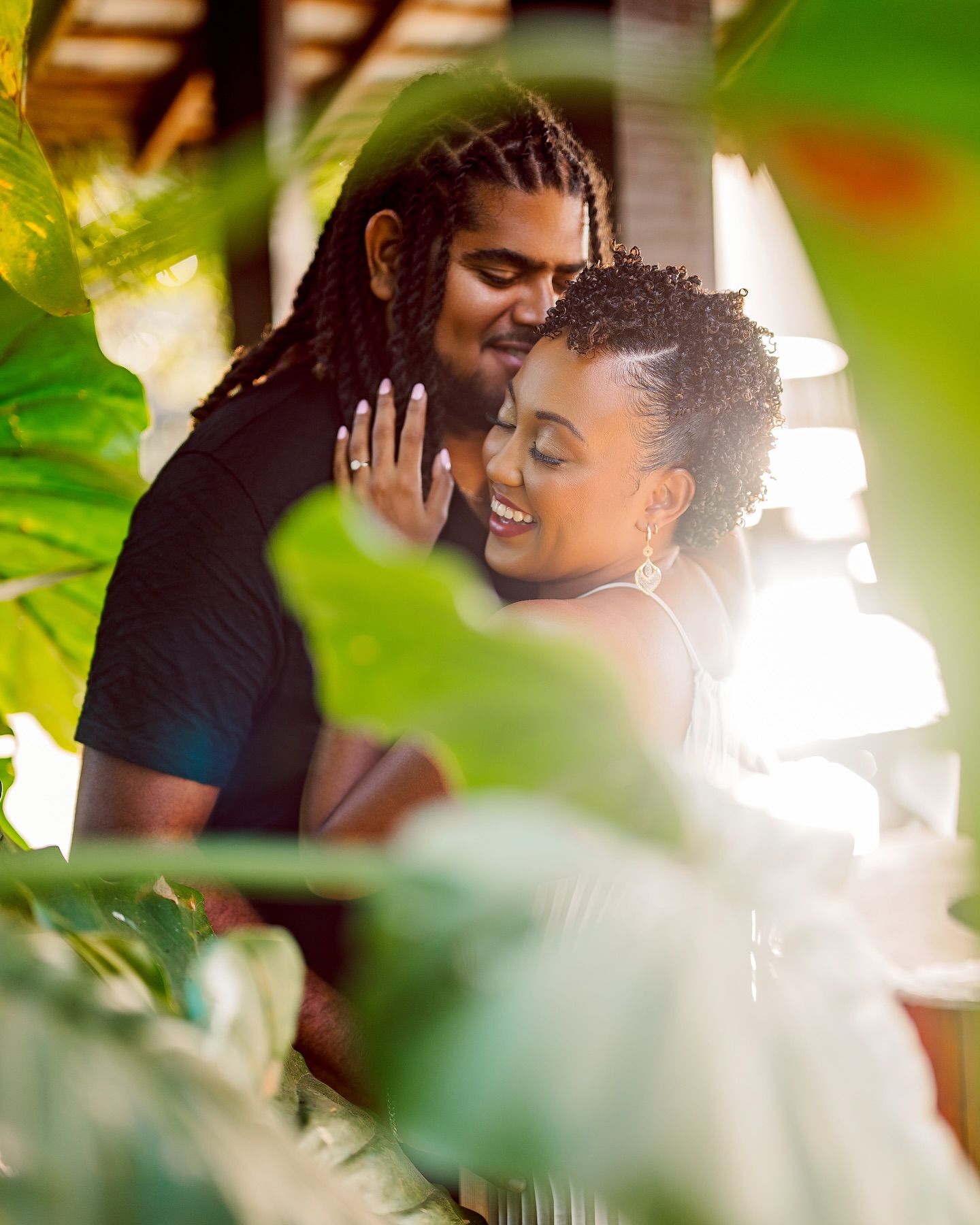 Intimate couple portrait through tropical foliage in natural lighting.