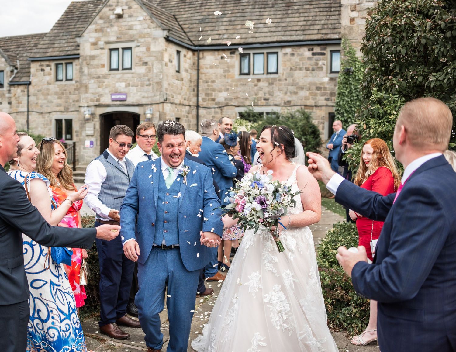 Wedding guests throw confetti over a newlywed couple outside Tankersley Manor Barnsley South Yorkshire