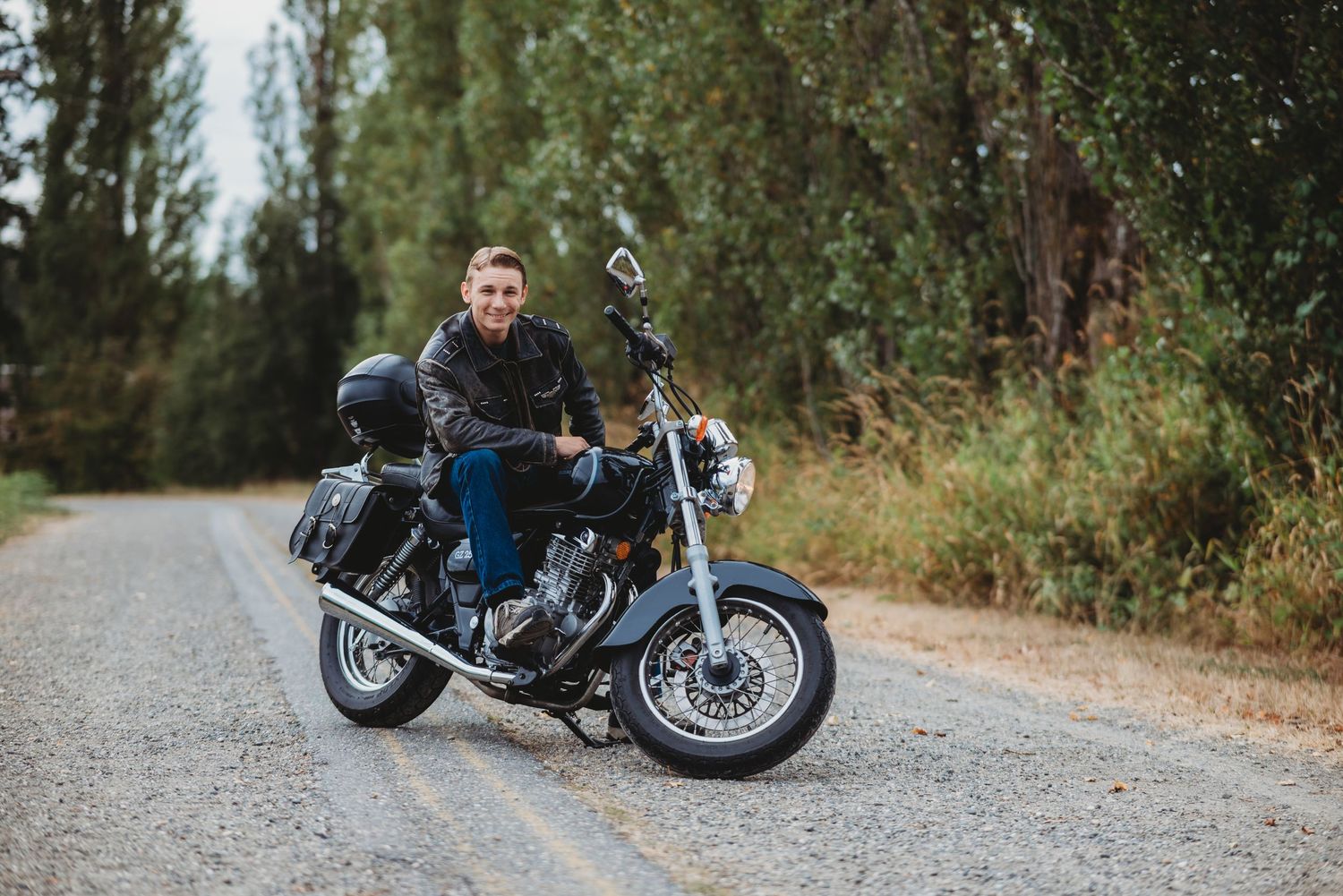senior guy smiles at the camera sitting on his motorcycle
