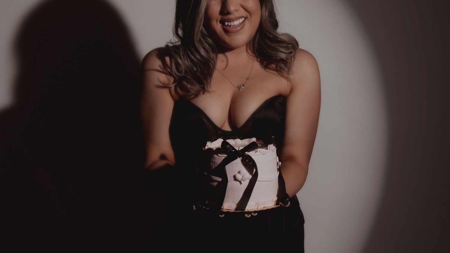Studio portrait with dramatic lighting and shadow against dark background.
