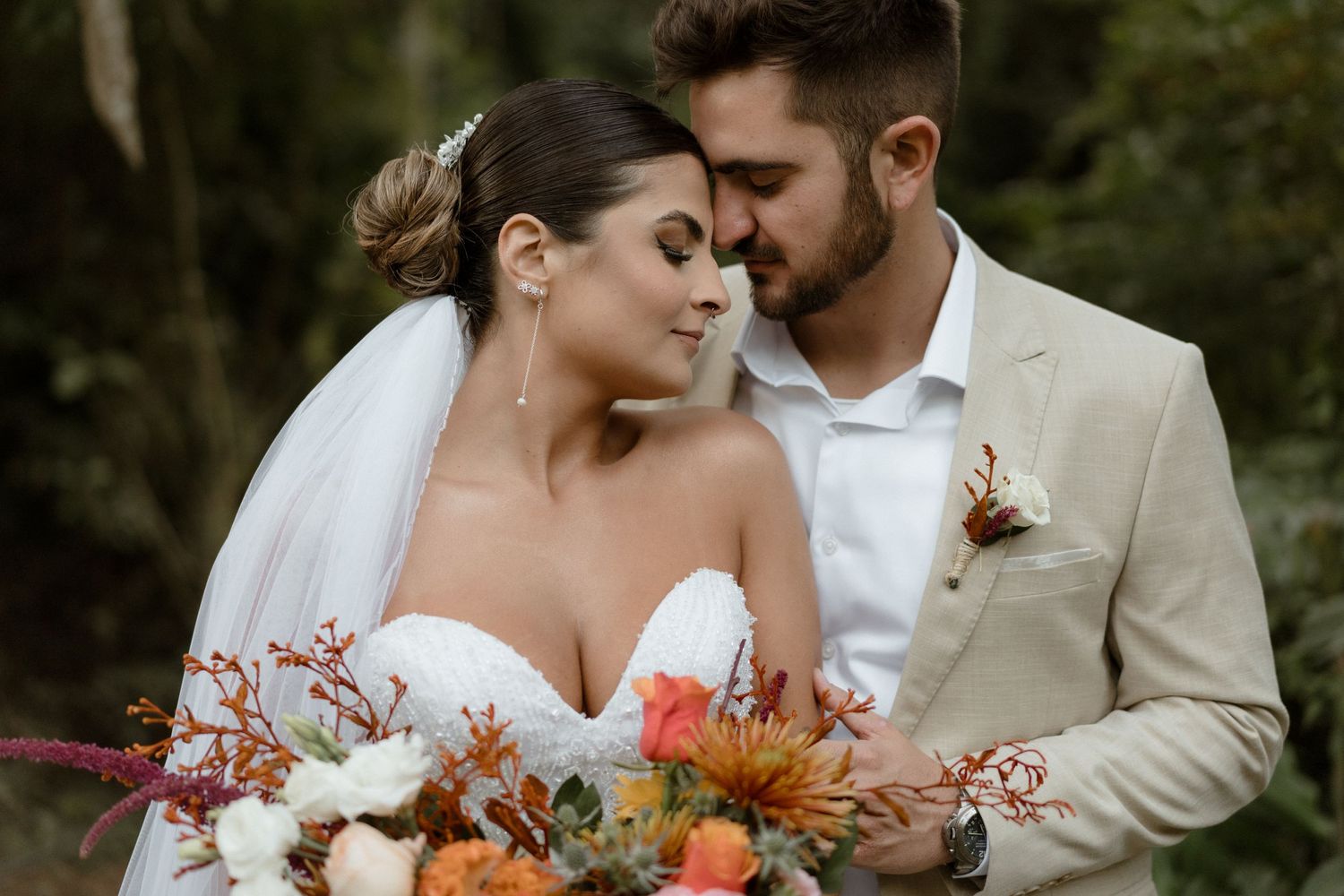 Intimate moment between newlyweds with autumn-colored floral bouquet.