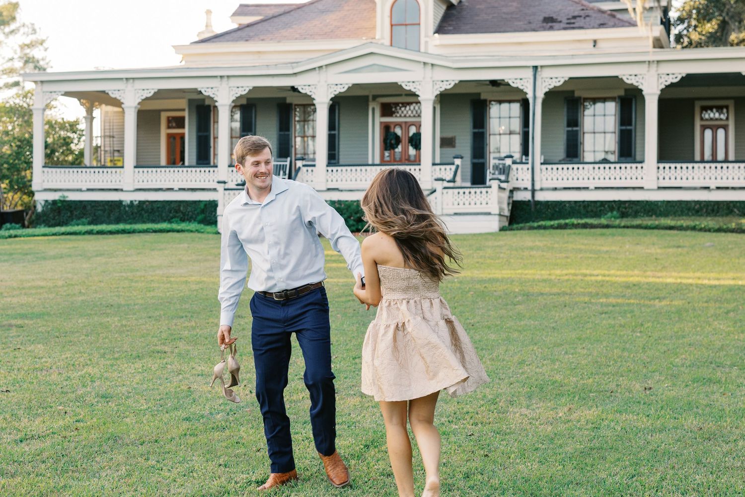 Couple playing on lawn in front of Southern plantation style house.