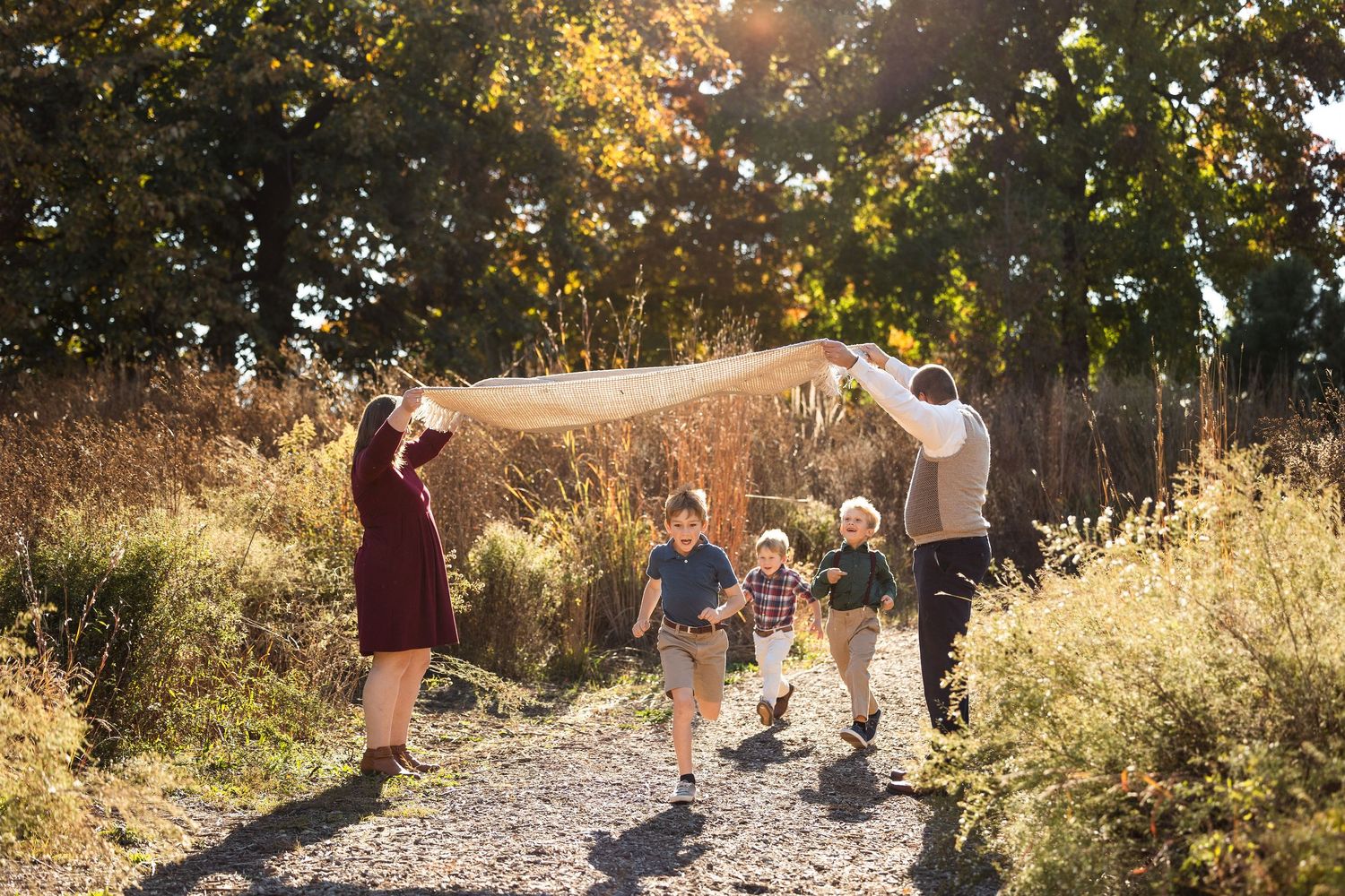 Family enjoying a golden autumn afternoon together on a scenic path surrounded by fall foliage.