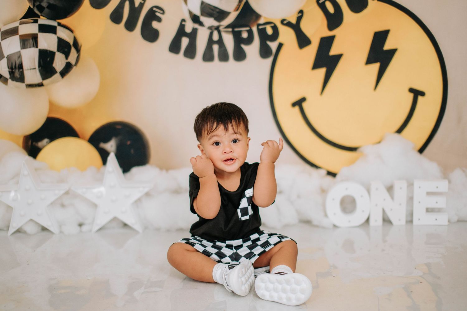 Black and white themed first birthday party setup with balloons, smiley face decor, and party decorations.