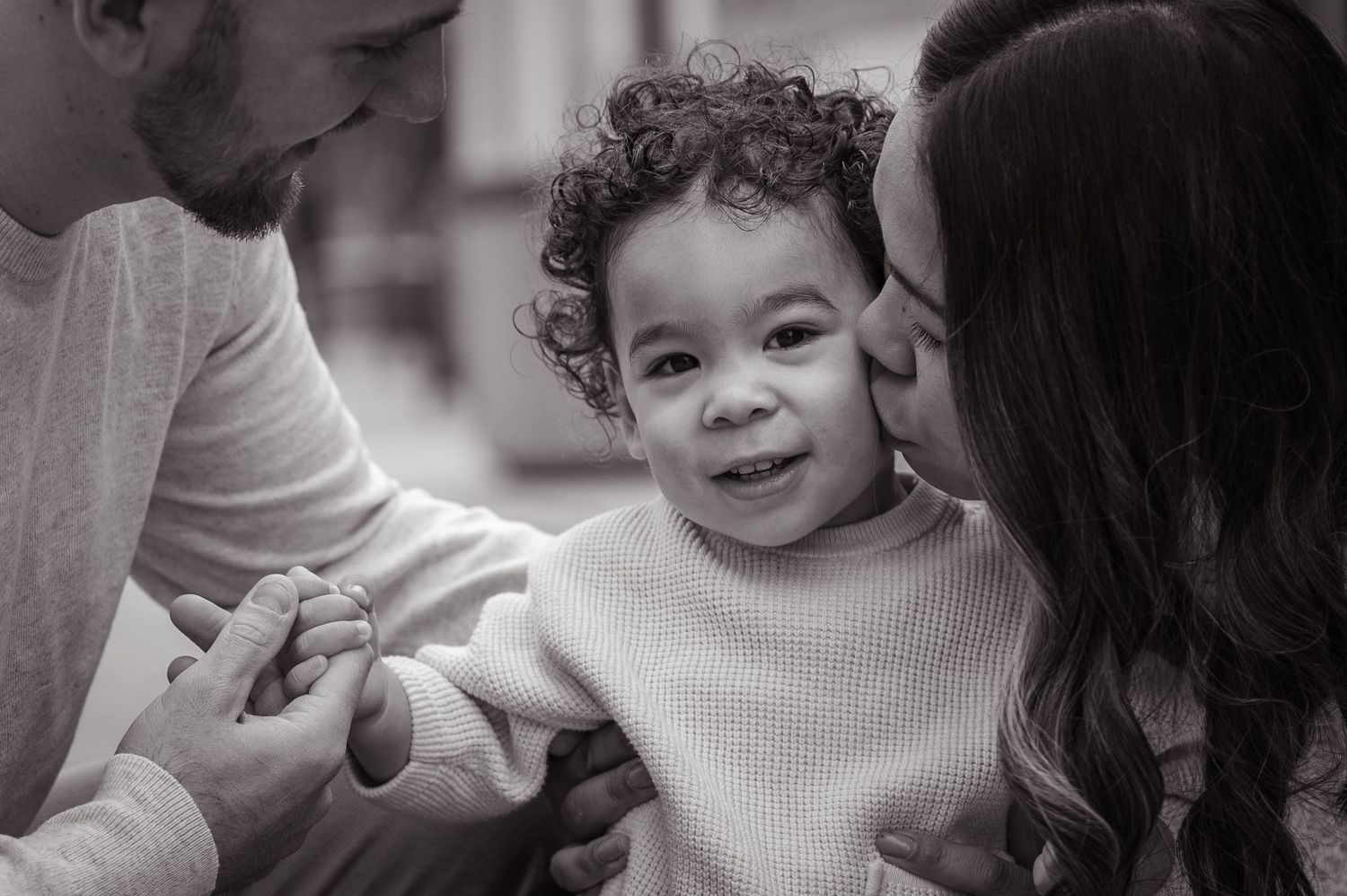 Intimate black and white portrait of a candid moment between child and parents.