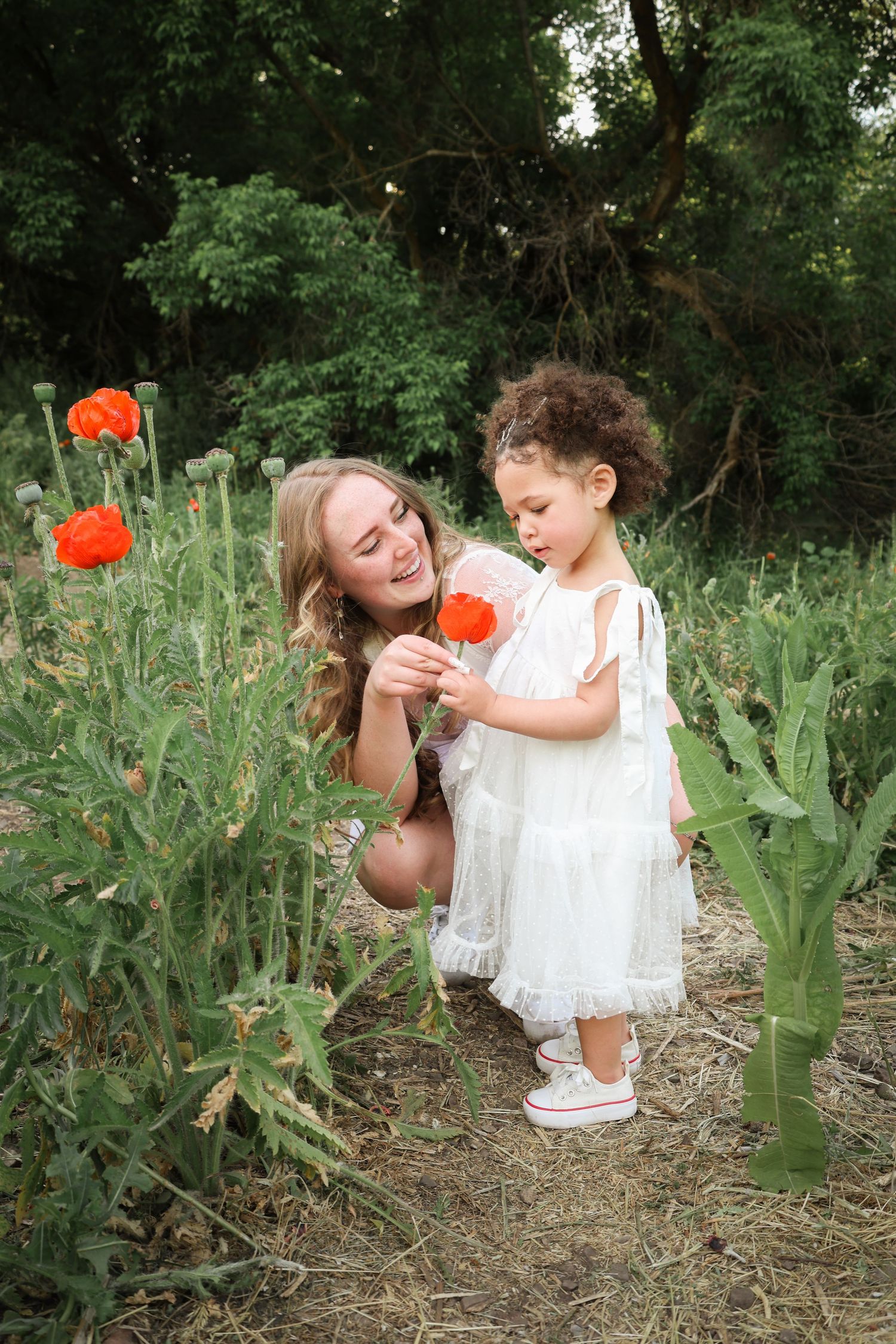 Mother and daughter sharing a joyful moment in a poppy field during golden hour, bathed in warm sunlight
