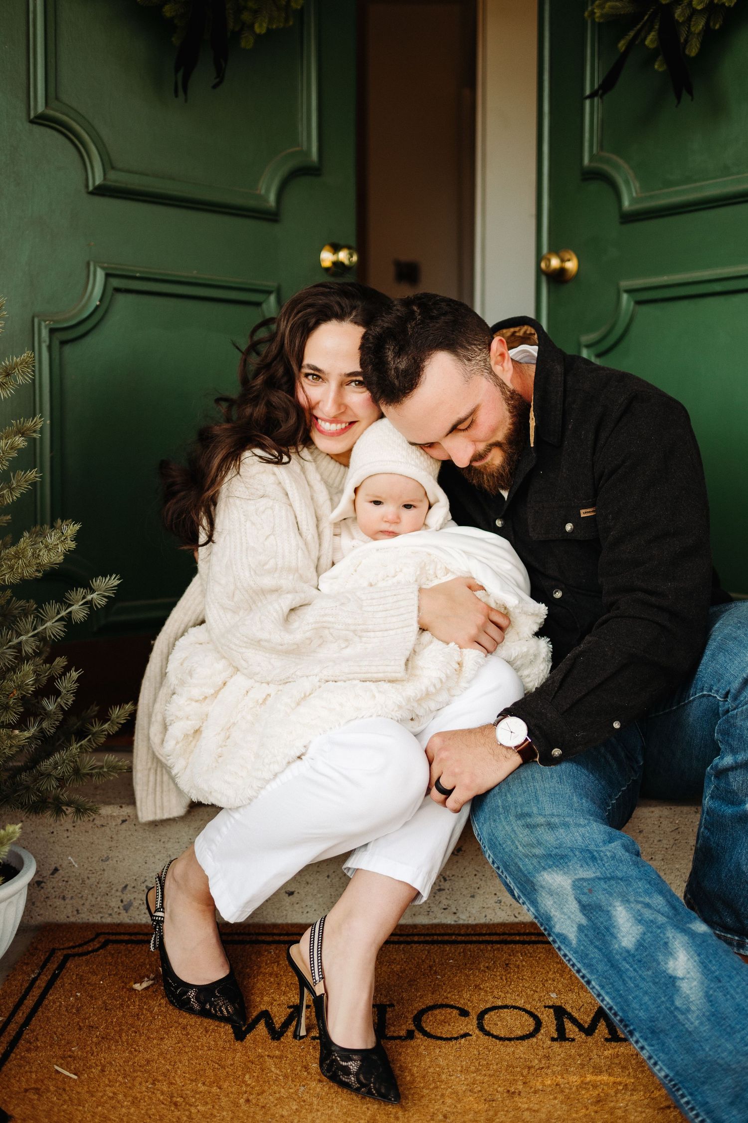 A sweet moment captured in a series of four photos showing a parent and baby in white christening attire on a doormat.