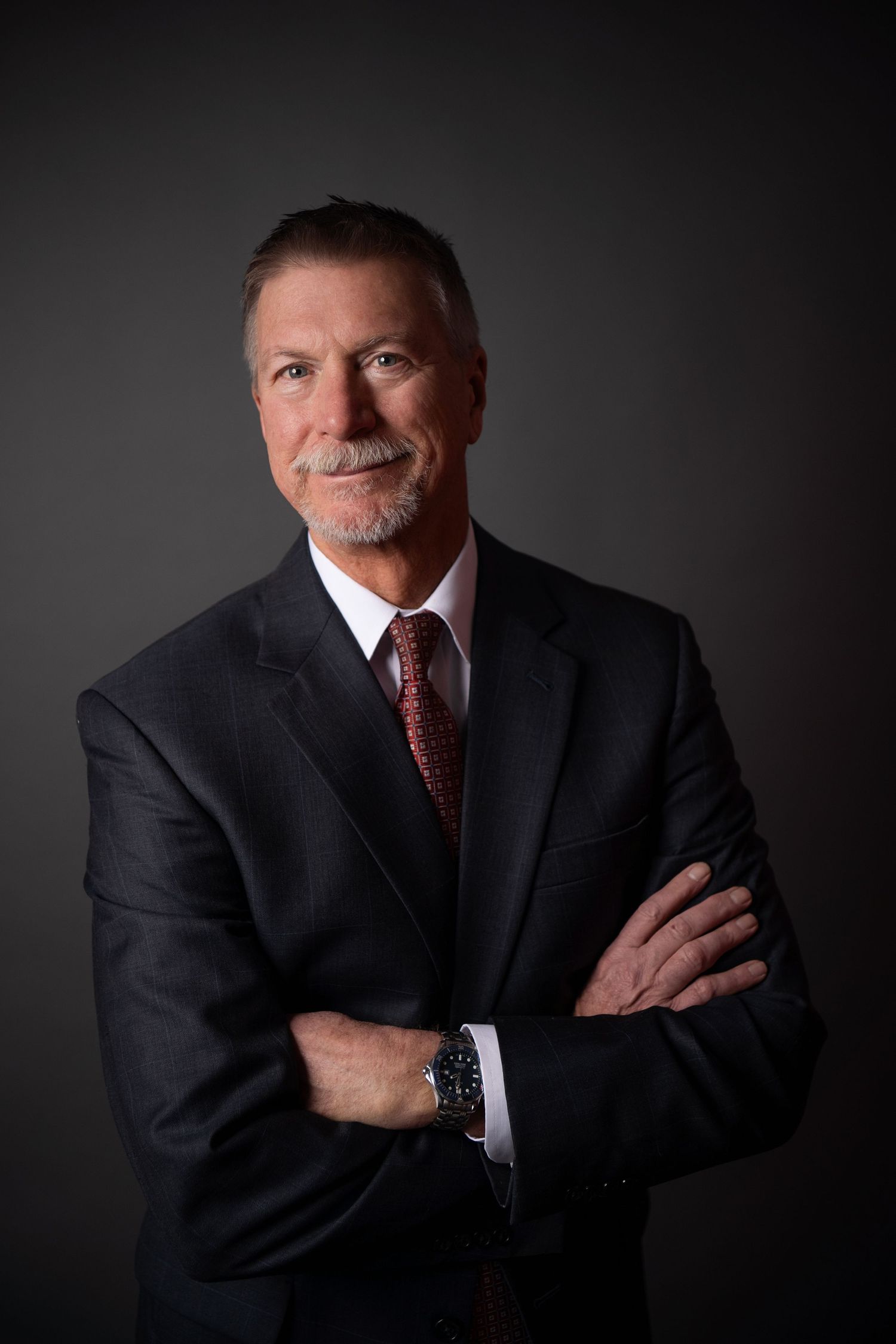 Professional portrait series showing a person seated on brown leather couches in a dark studio setting.