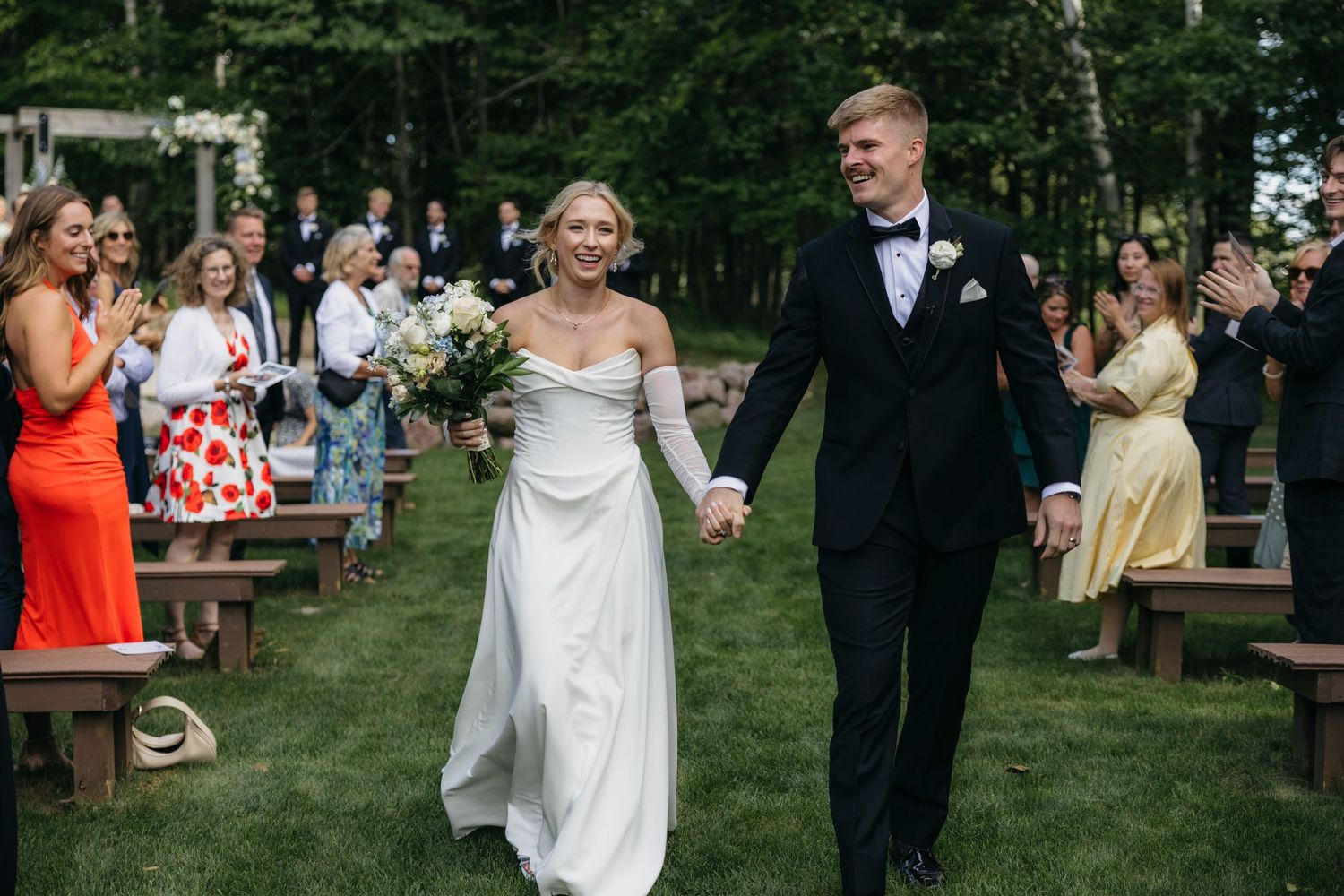 A tender moment between newlyweds during an outdoor wedding ceremony in a lush forest setting.