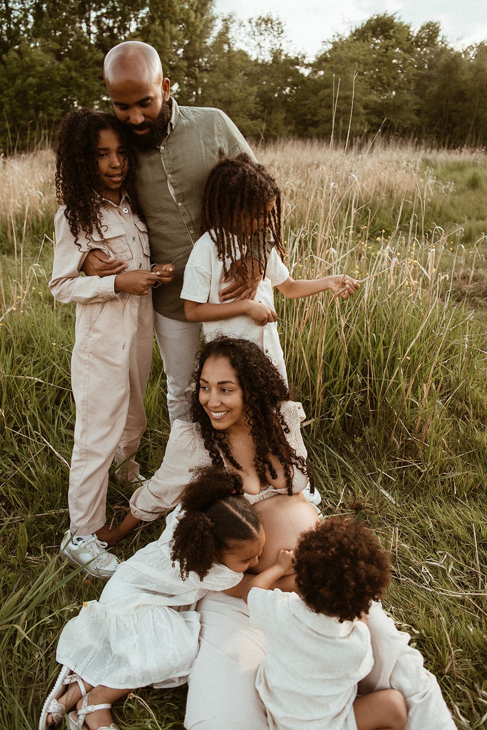 Manchester family photographer captures a family shares joyful moments together while sitting in a tall grass field during golden hour.