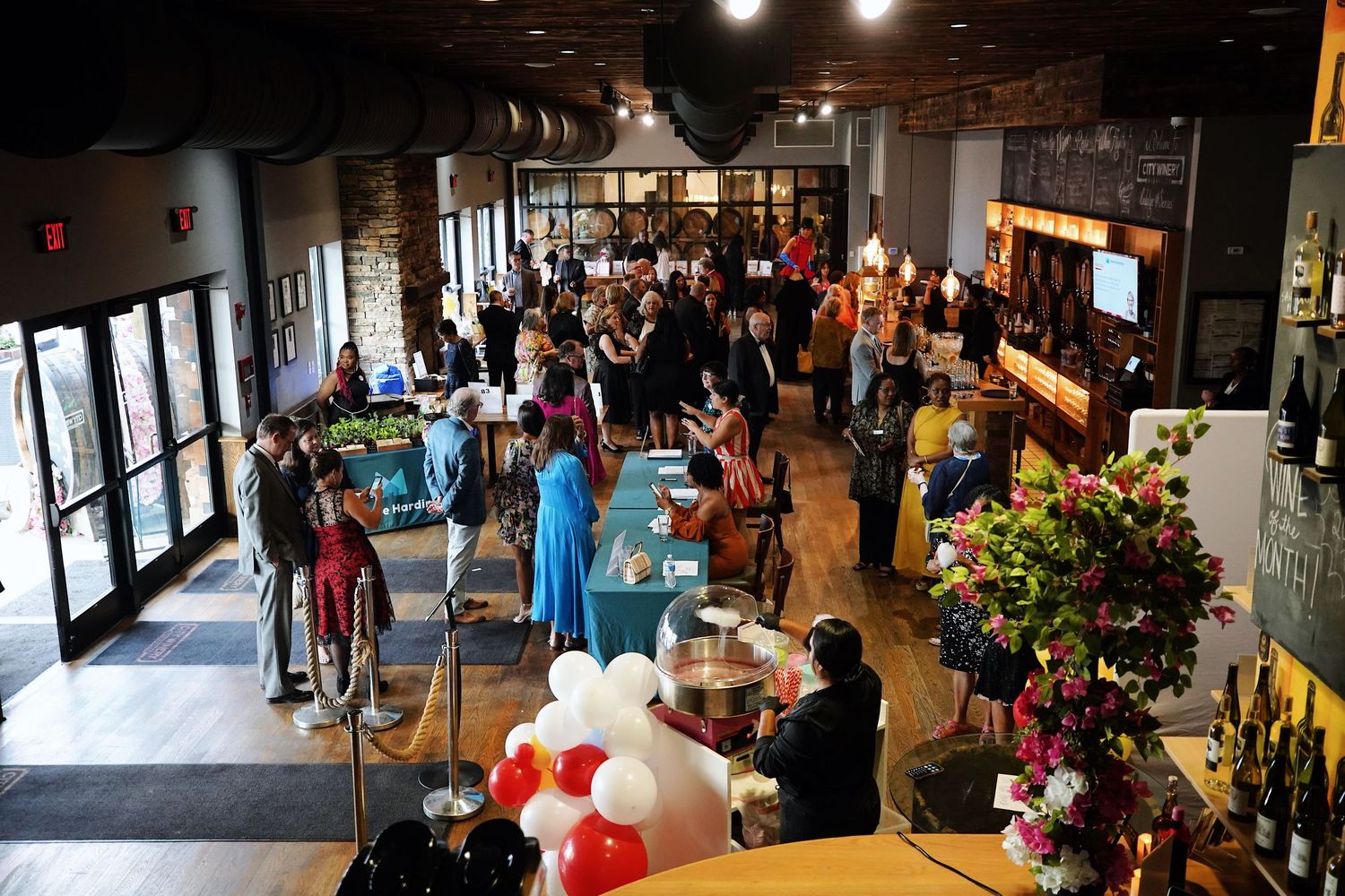 Modern event space filled with people and decorative balloons.