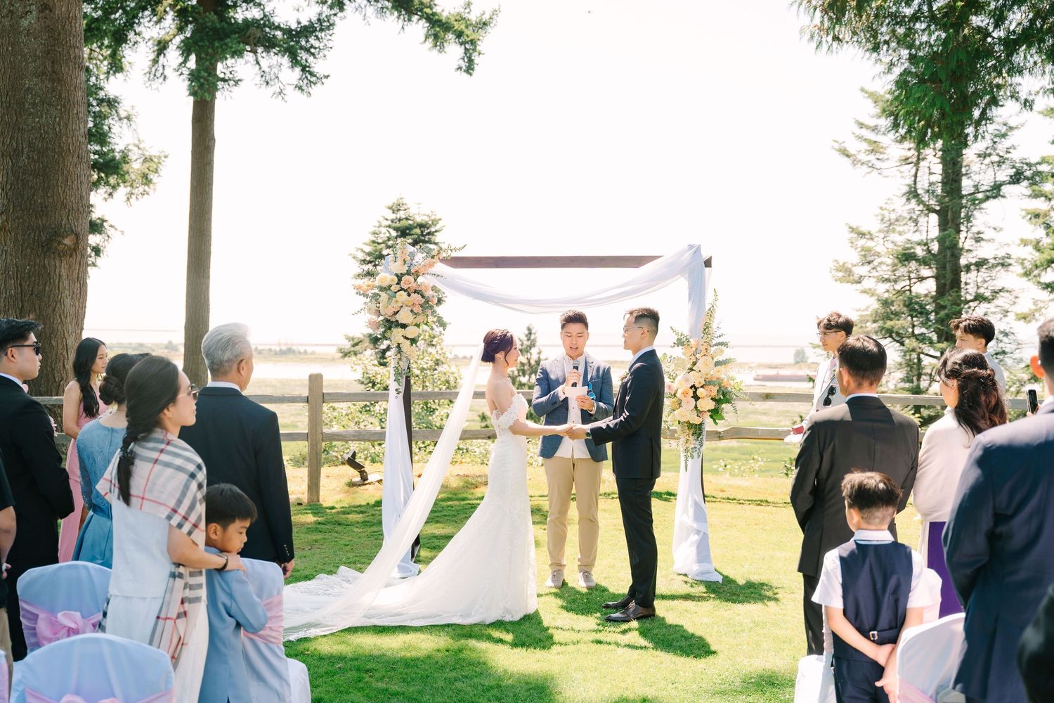 A panoramic collage of an outdoor wedding ceremony with guests gathered under trees near the water at sunset.