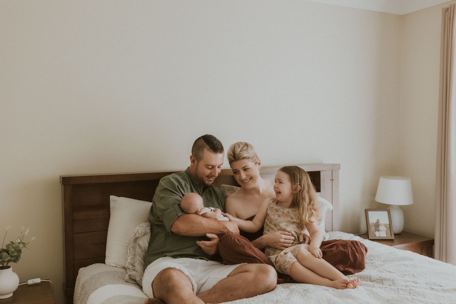 Casual family relaxing together on bed in natural morning light.