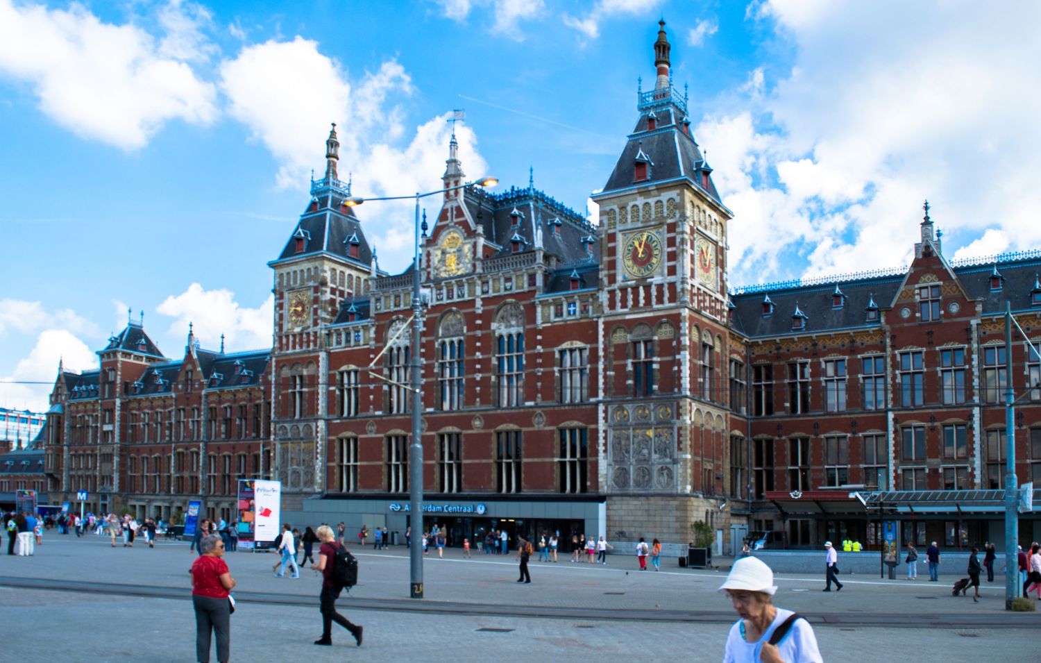 Historic Amsterdam Central Station building with its ornate red brick architecture and gothic towers.