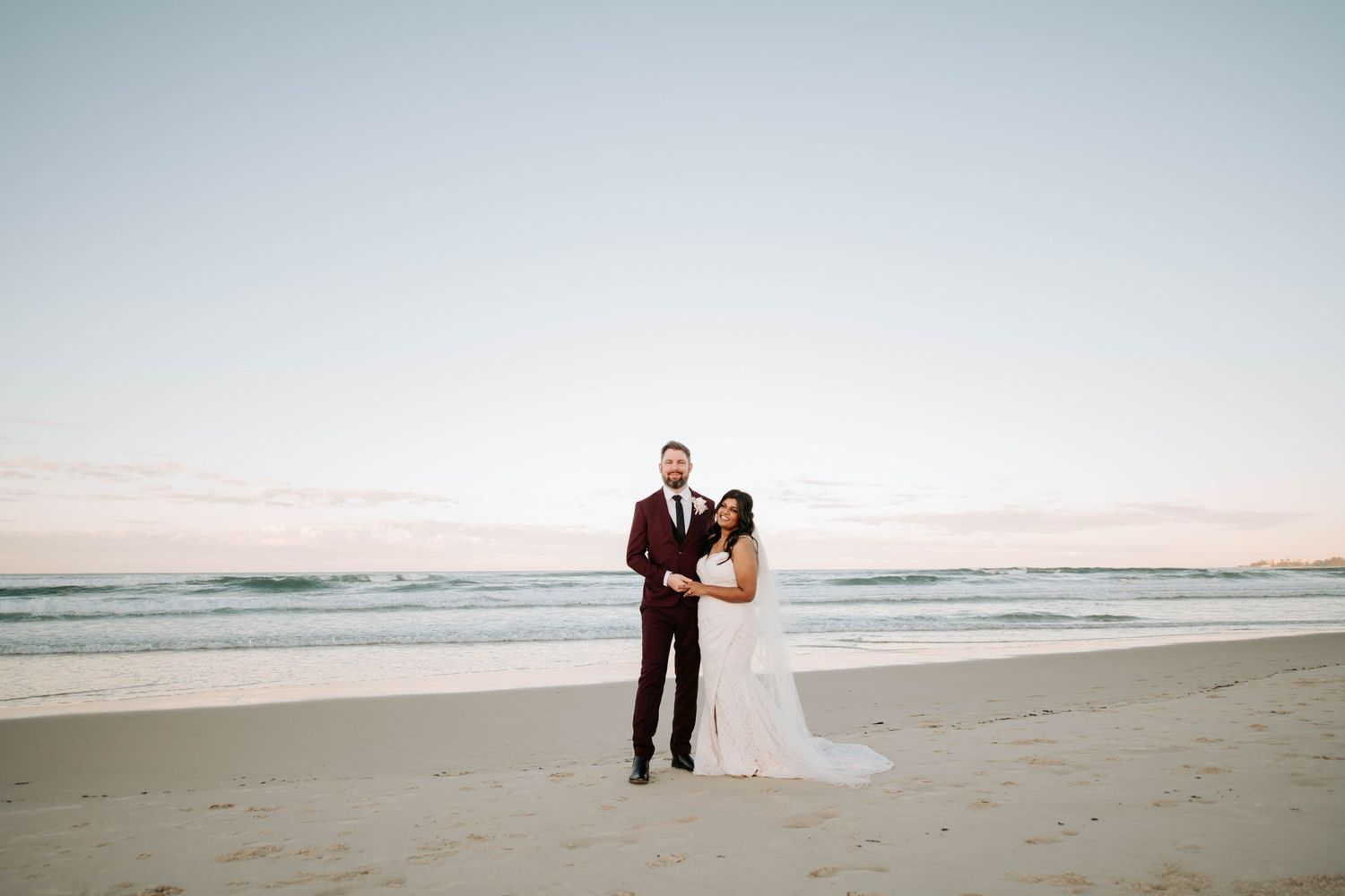 A romantic sunset beach wedding photo capturing a couple standing together on the sand.