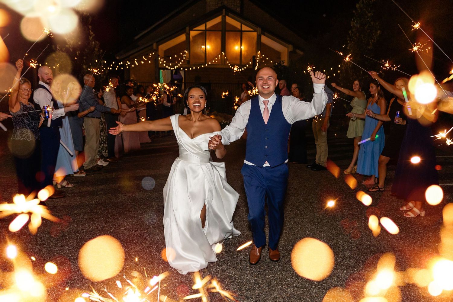 Wedding guests holding sparklers creating a glowing tunnel at an outdoor evening celebration at Villa Aletta in Omaha, NE.
