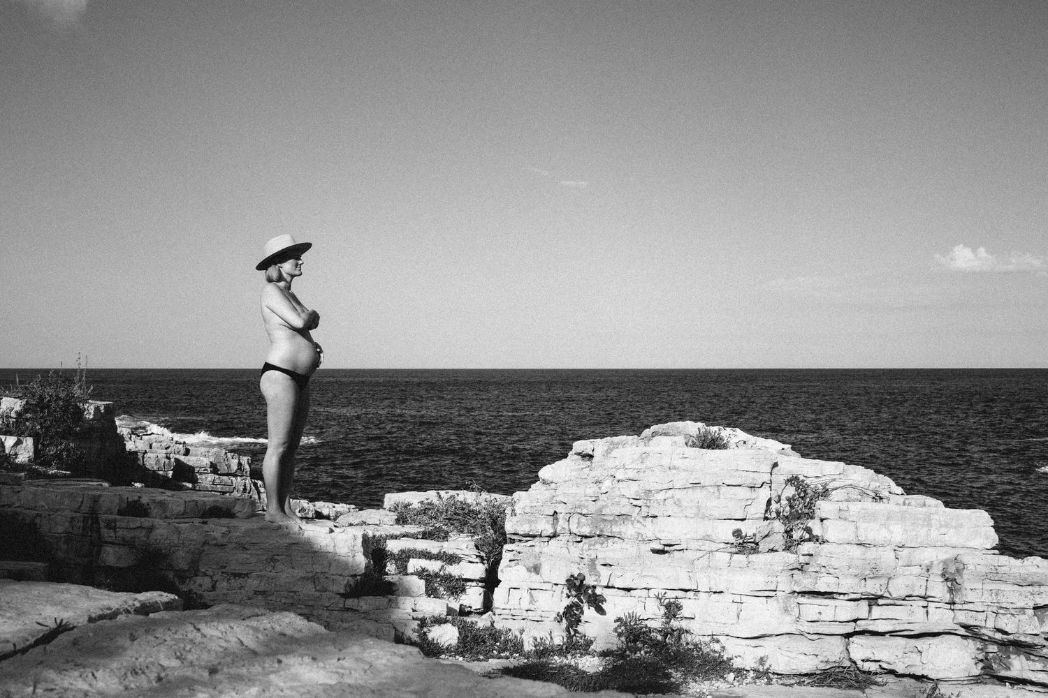 Cliffside divers leap off the white limestone coast of the Mediterranean Sea in black and white photography.