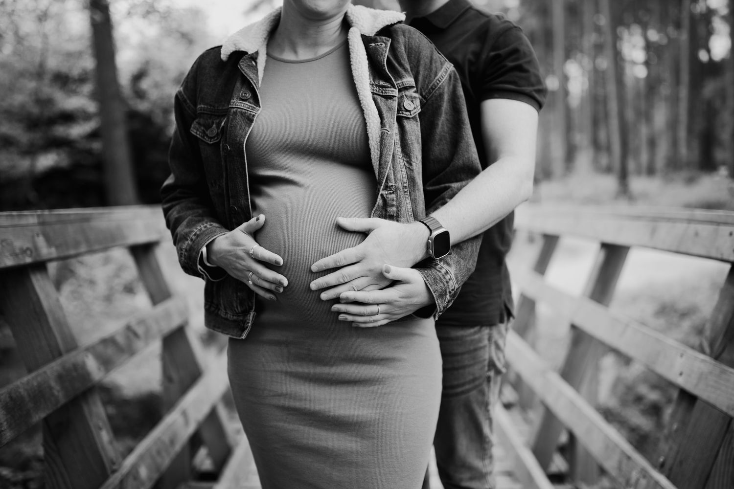 Black and white maternity photo series showing intimate moments between expecting parents outdoors in nature.