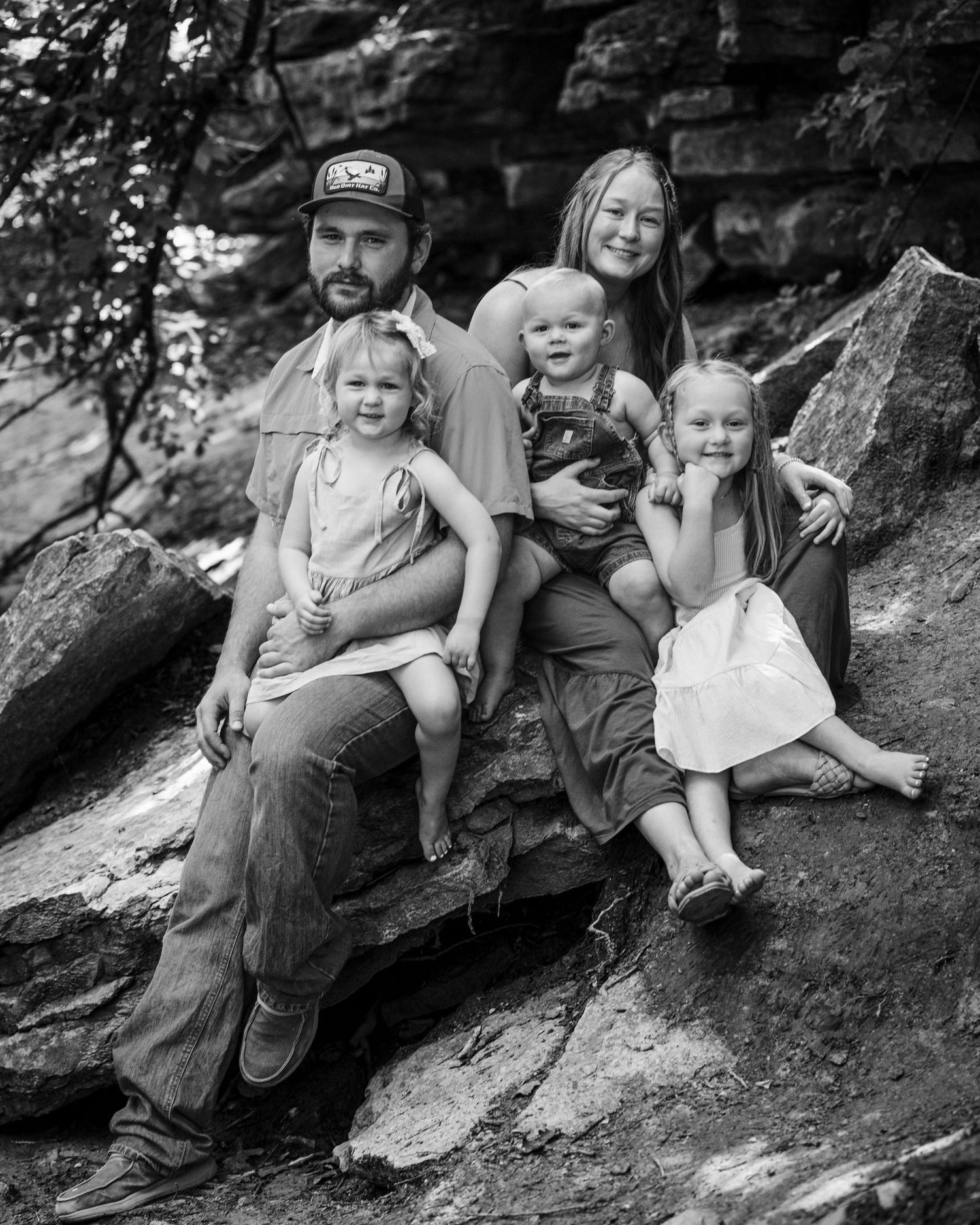 Black and white photographs of family members sitting together on a rocky hillside slope in casual outdoor poses.