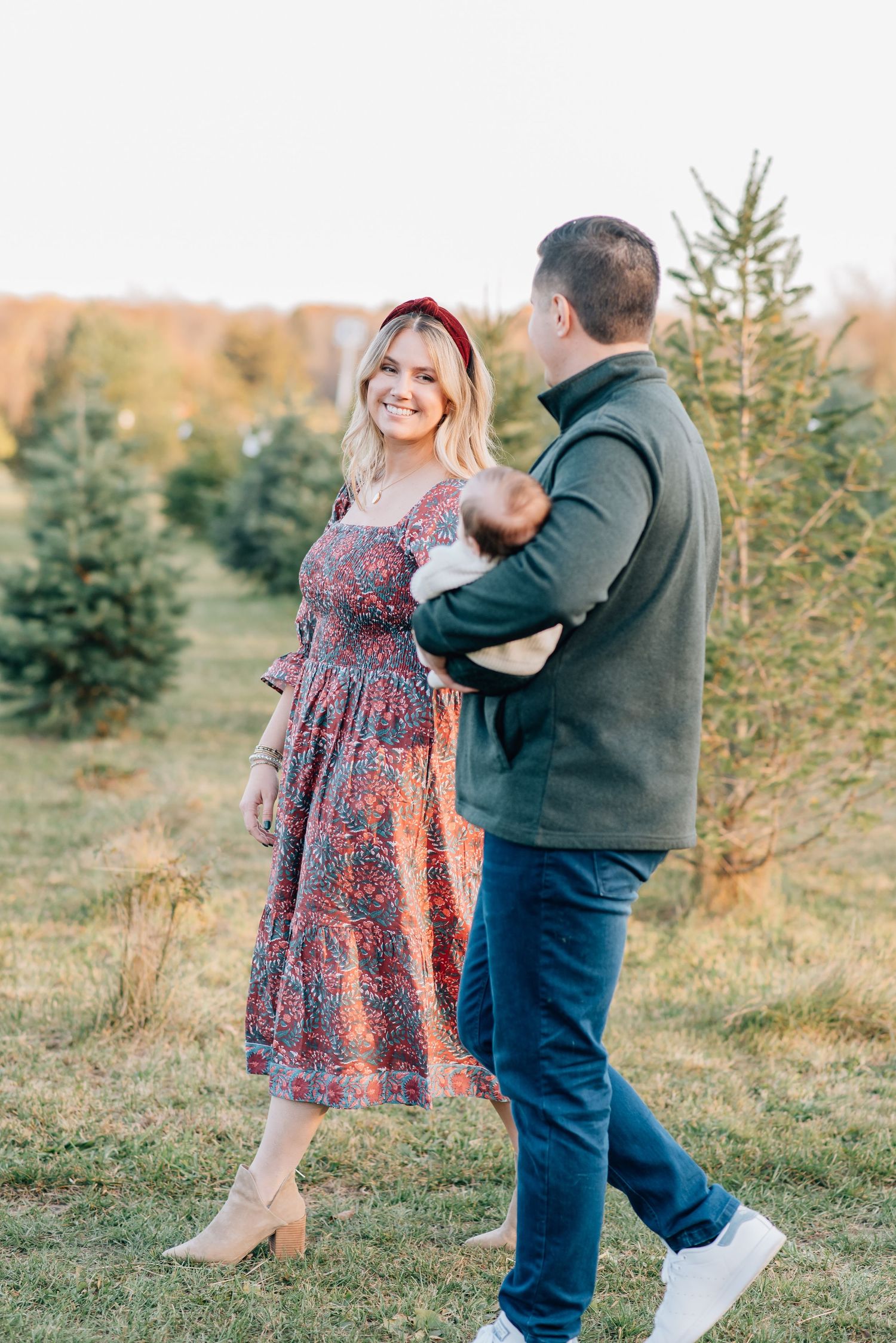 A mother and father walk through a tree farm for a holiday mini photo session in Wall Nj.