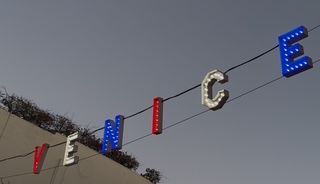 Illuminated PEACE sign with red and blue letters against dark sky.