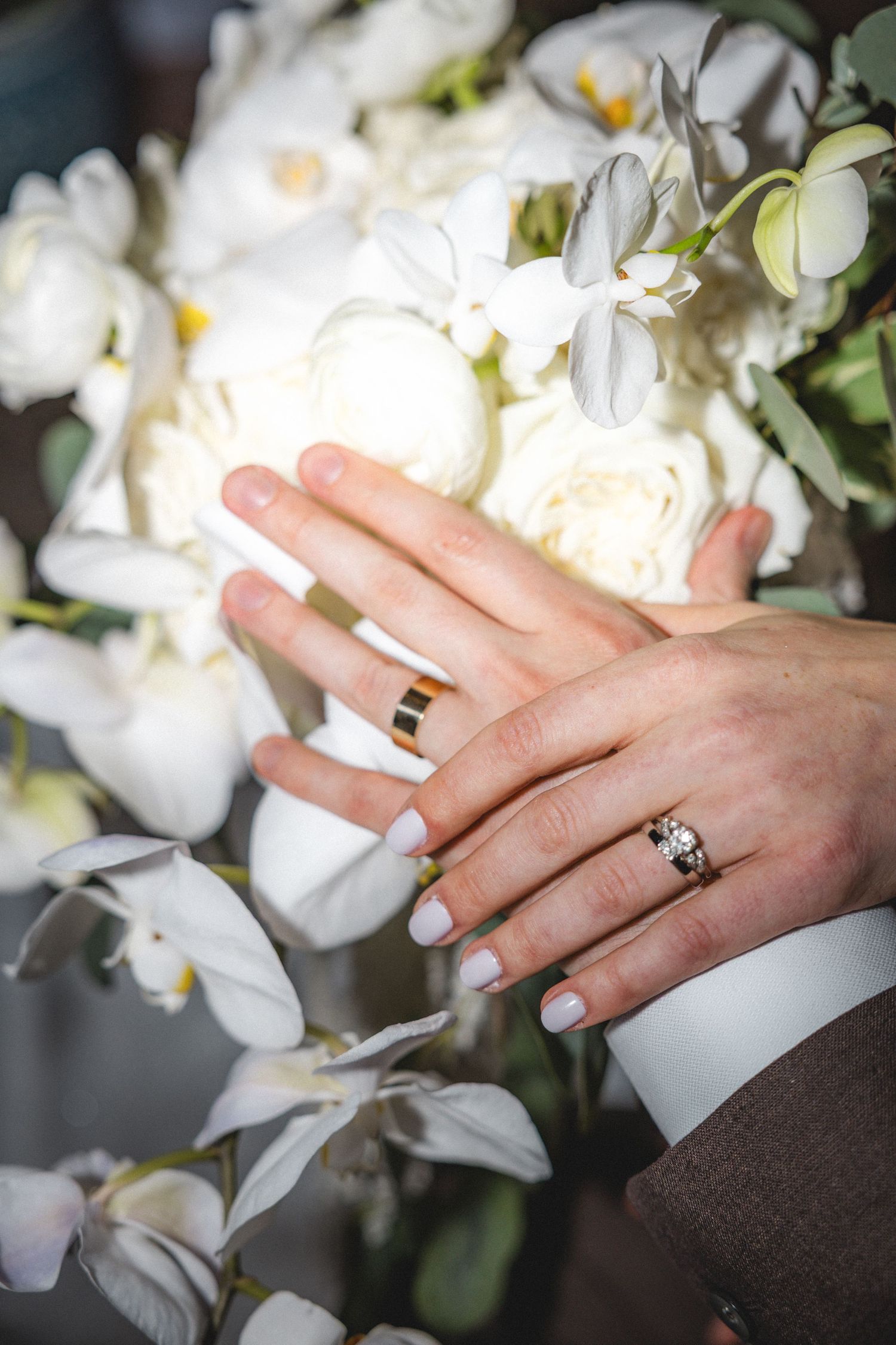 Wedding rings displayed on hands against white floral background in a sequence of close-up detail shots.