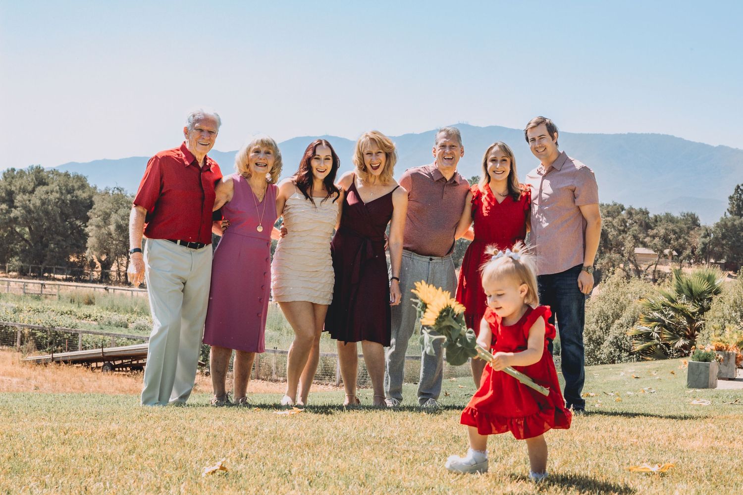 Extended family poses together in an outdoor field with mountains in the background wearing coordinated outfits.