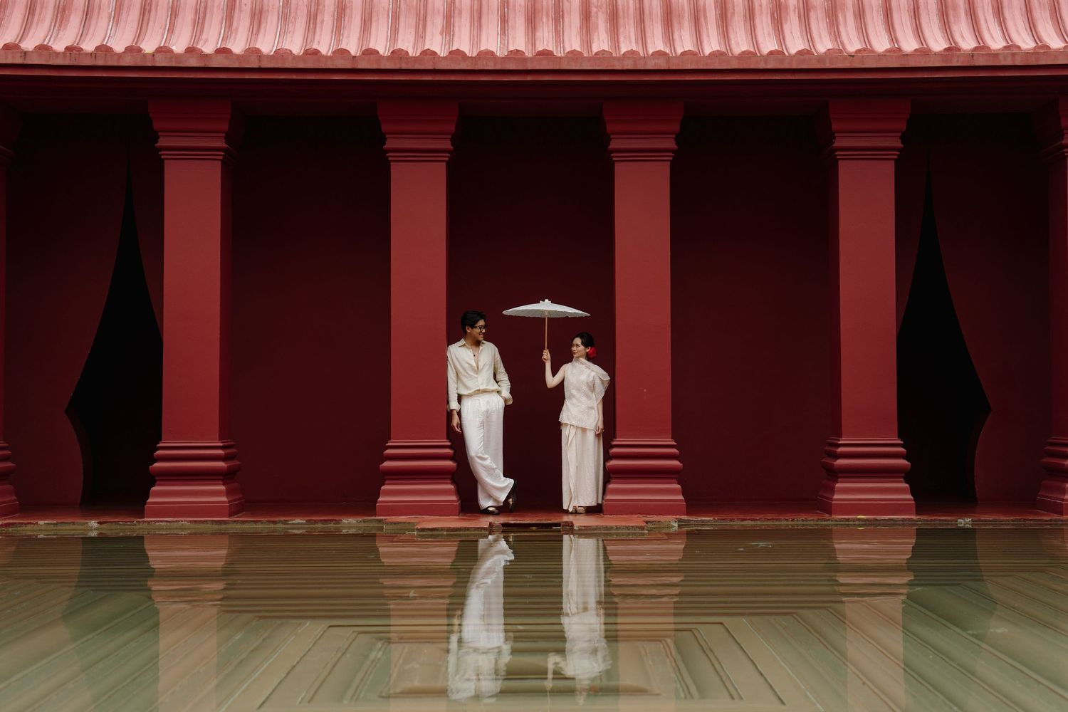 A traditional Asian architectural setting with red columns and reflective flooring.