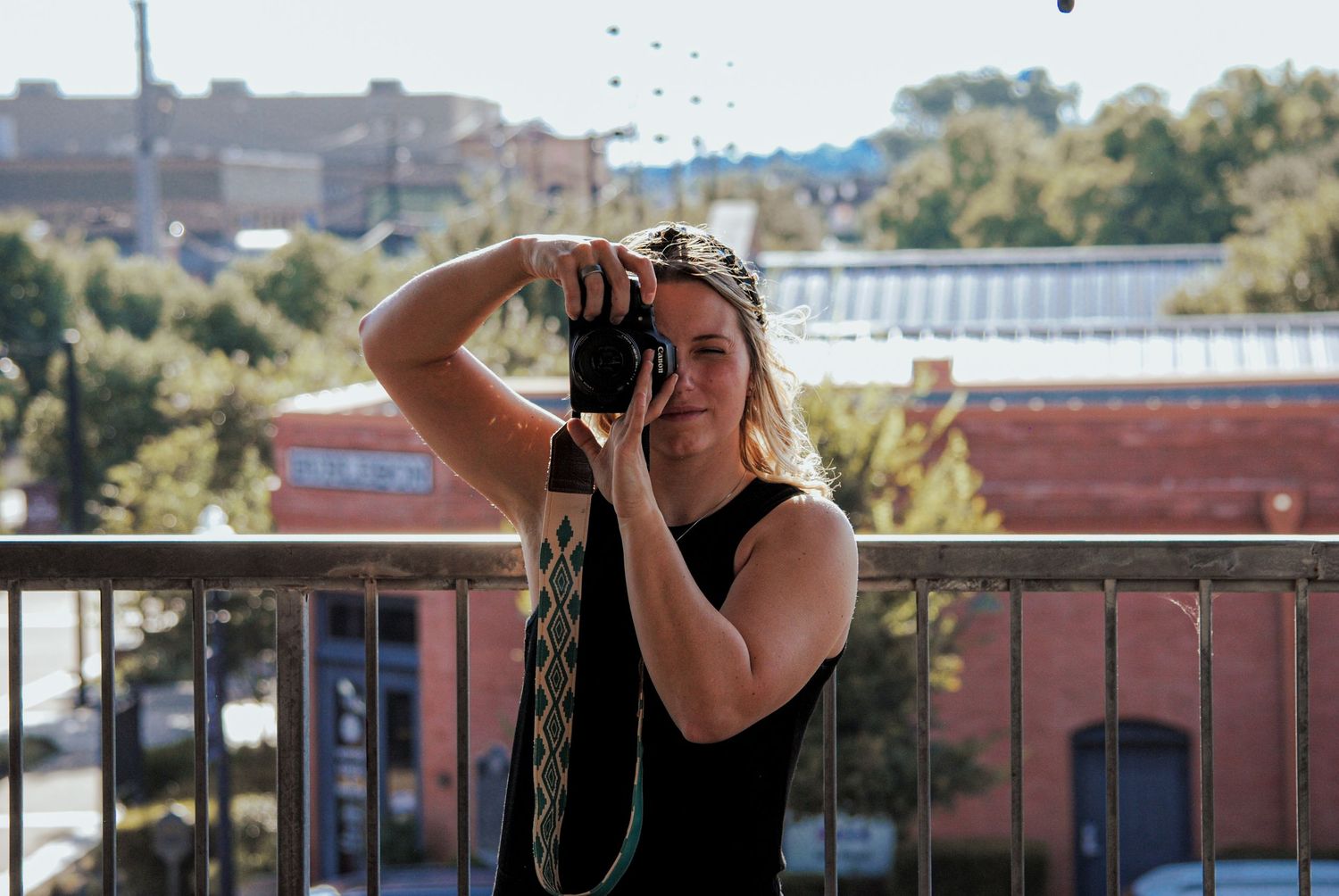 A series of photographers in black clothing take photos from a rooftop overlooking an urban landscape.