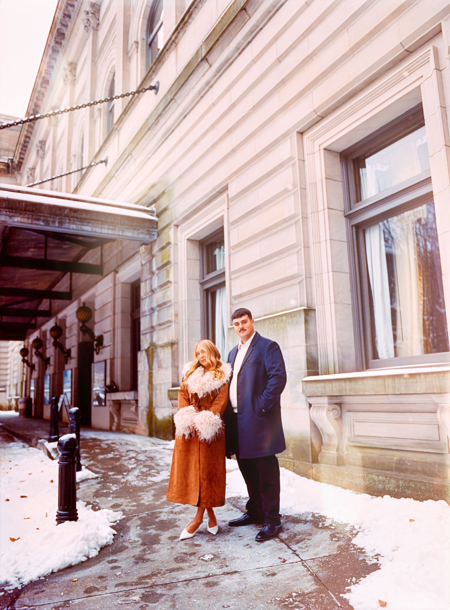 Couple outside carnegie fine arts museum for engagement photos taken on film photography.