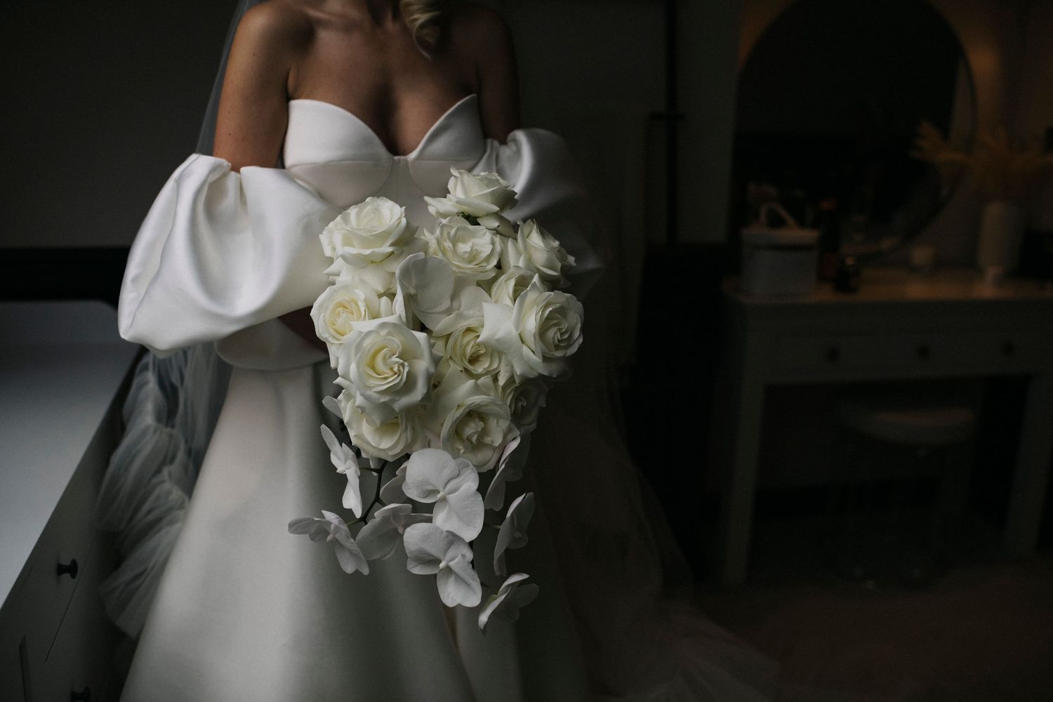 White orchid wedding bouquet with cascading flowers and delicate greenery creates an elegant bridal arrangement.