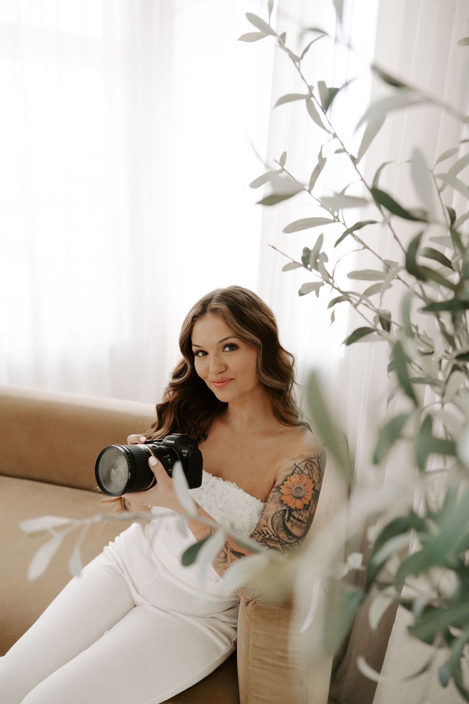 Romantic boudoir photoshoot with soft natural lighting and green foliage in the background.