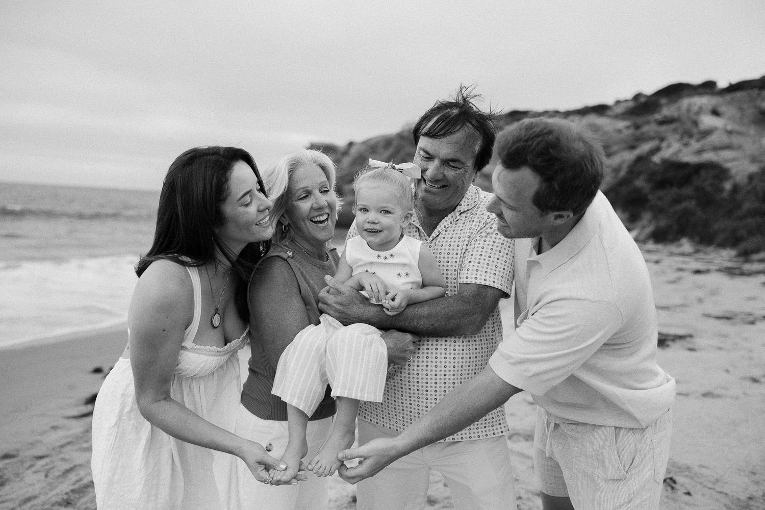 A series of black and white photos showing tender family moments together at the beach.